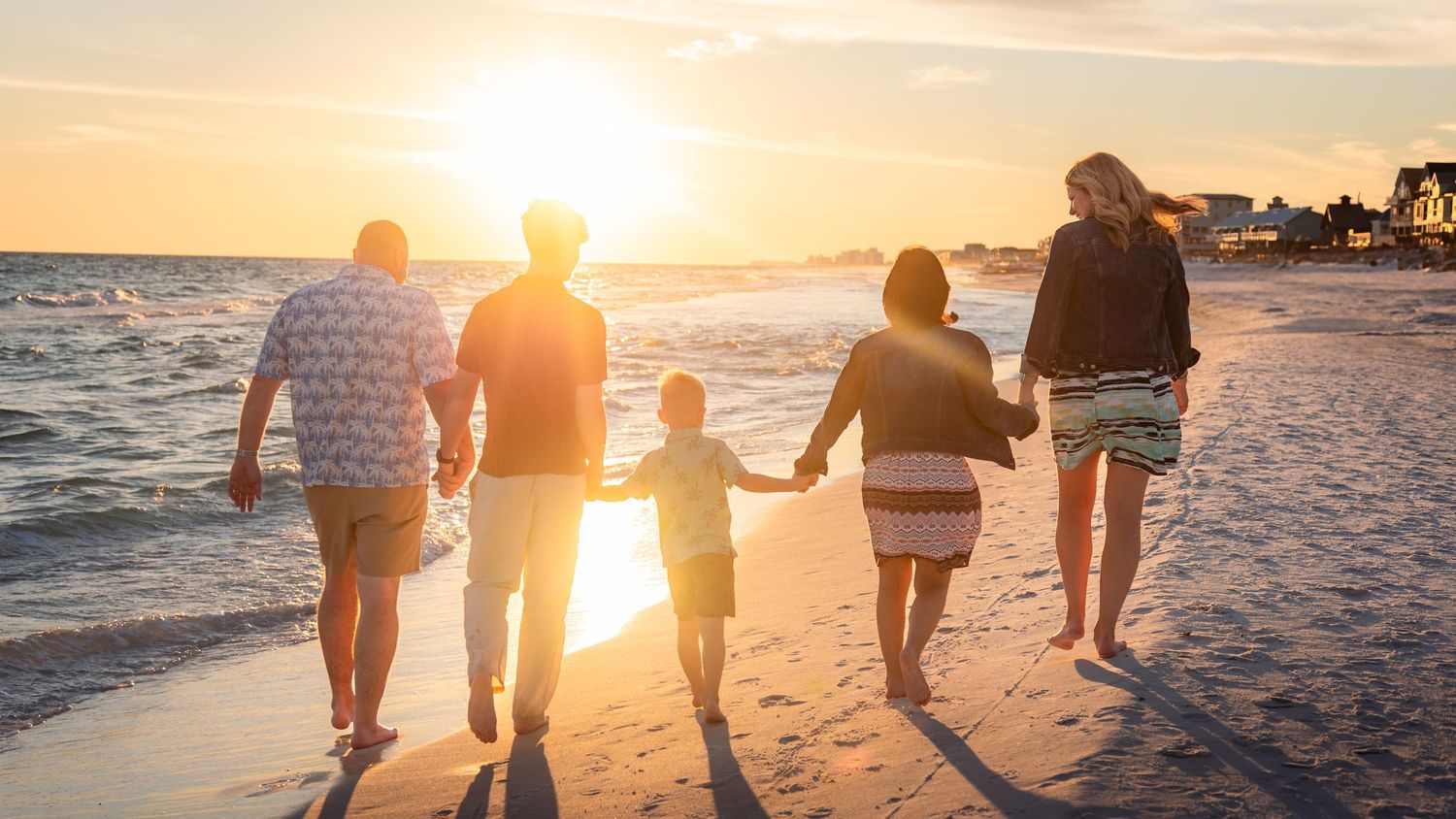 Family session on the beach, showing a family of five walking away holding hands. JDalbey Photography — family portraits in Champaign, IL.