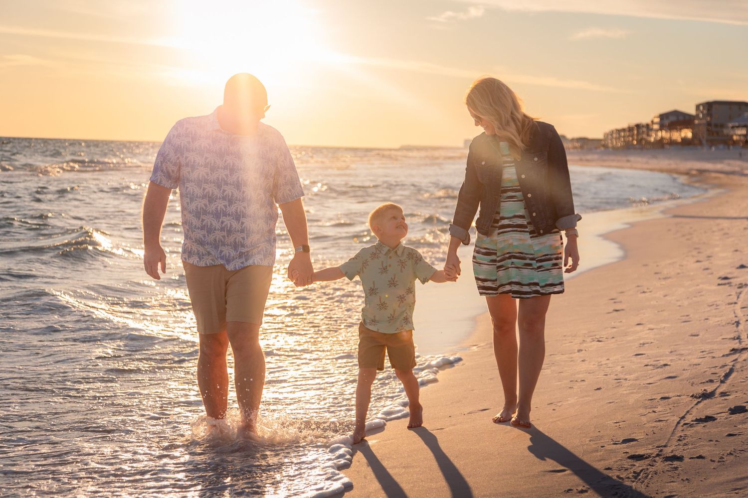 Family session on the beach, showing a family of three walking holding hands. JDalbey Photography — family portraits in Champaign, IL.