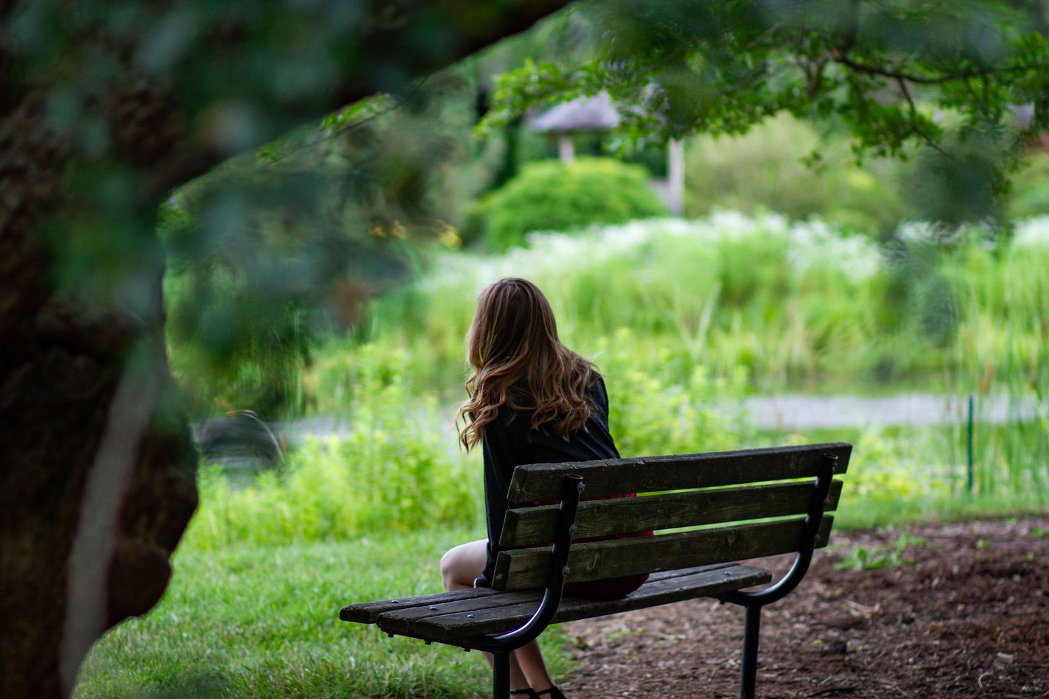 Senior portrait at Arboretum, showing girl sitting at bench looking at lake. JDalbey Photography — Champaign IL senior portraits.
