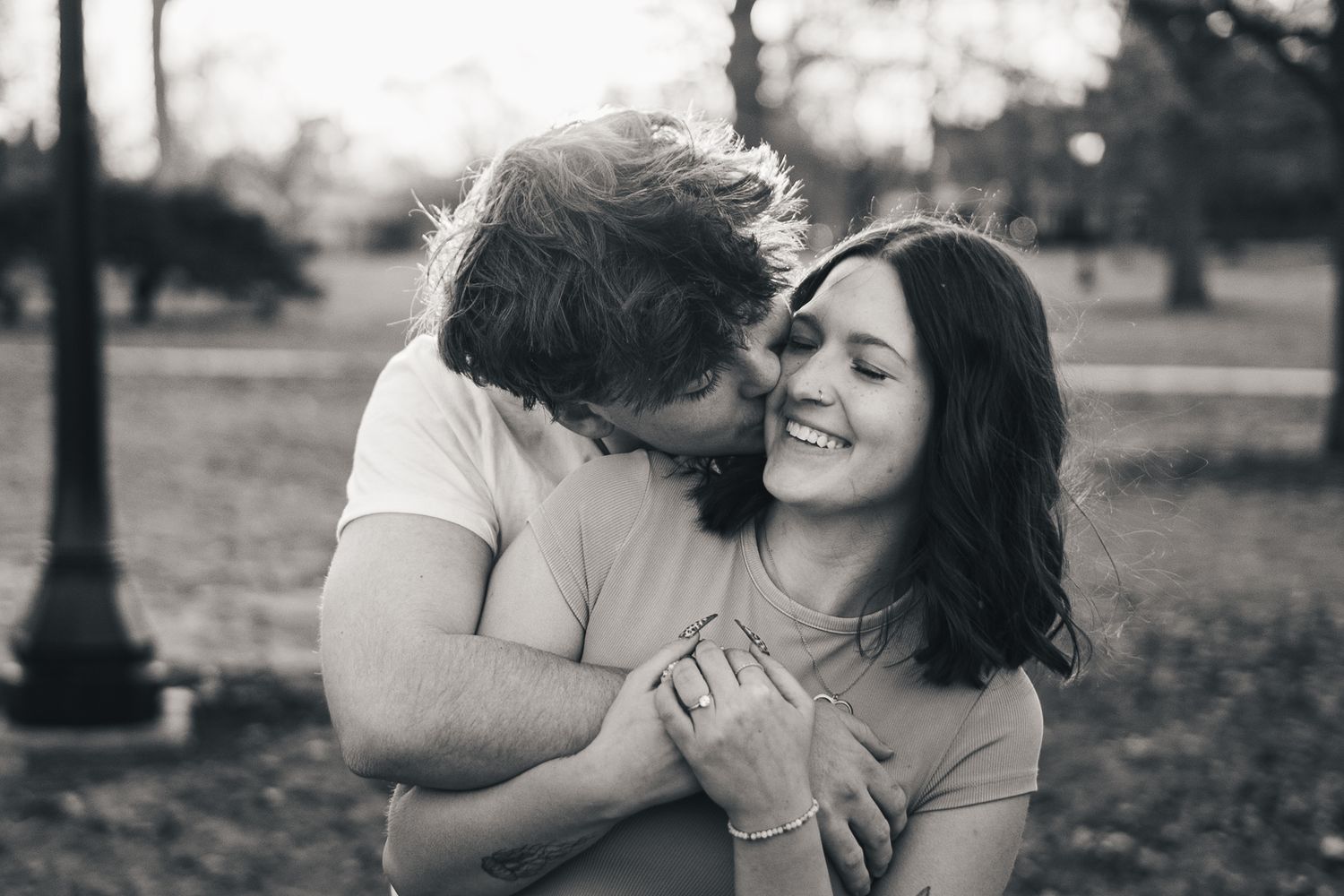 Couples photo in West Side Park capturing a man hugging and kissing his girlfriend. JDalbey Photography — couples portraits in Champaign IL.