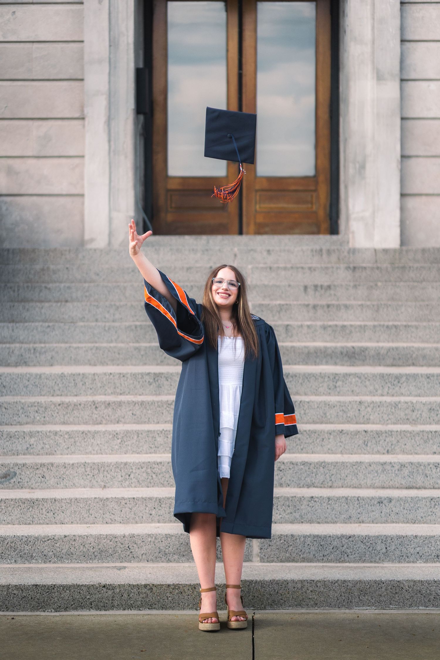 Senior portrait in downtown Champaign, showing girl throwing graduation cap. JDalbey Photography — Champaign IL senior portraits.