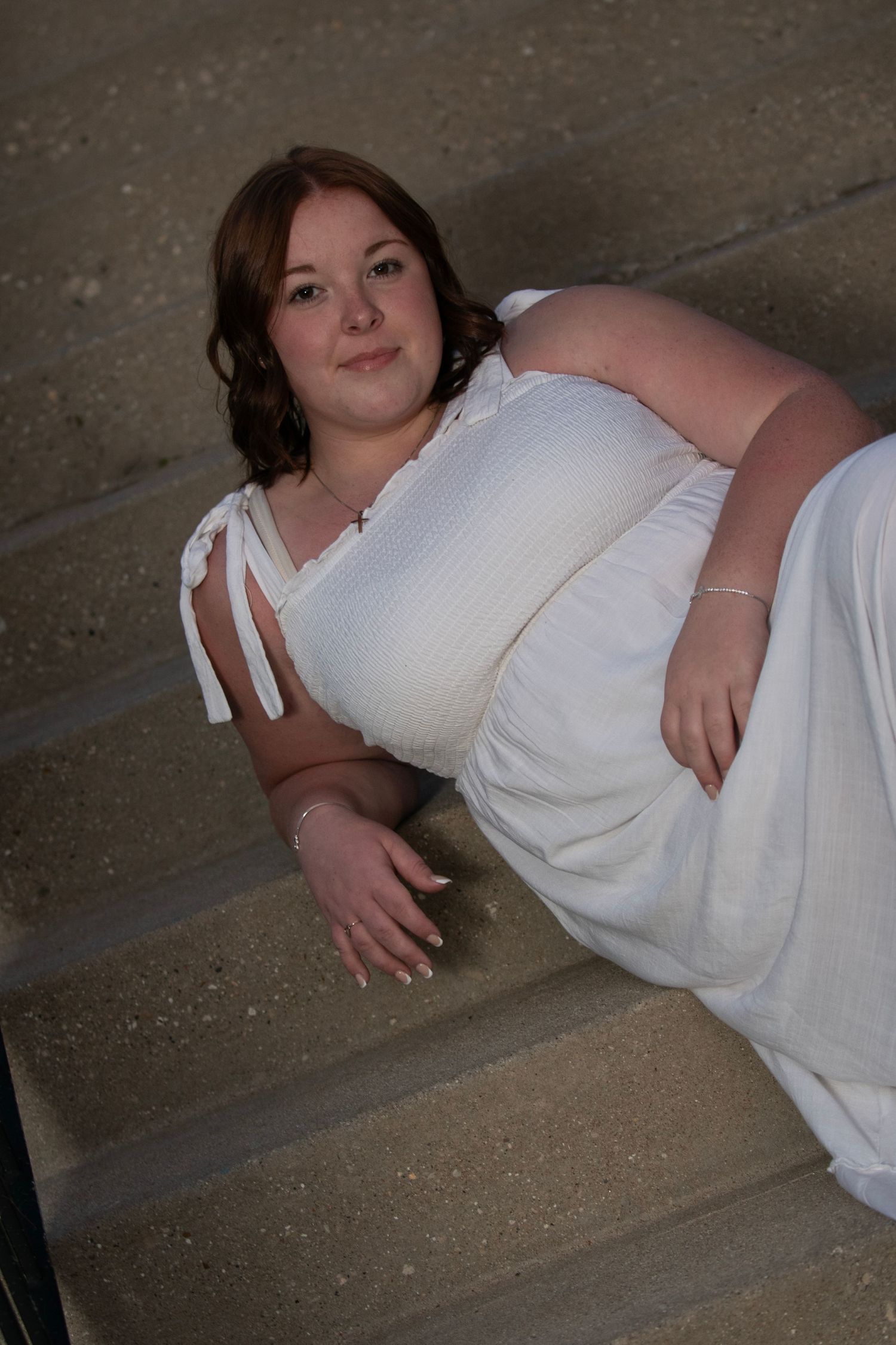 High School Senior in white dress posing on concrete steps during her senior portrait experience with Simply Junique in Milwaukee.
