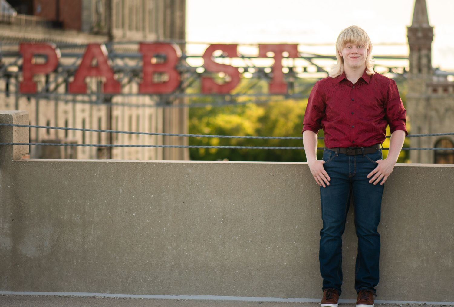 High school senior poses in front of the Pabst Brewery commercial signage for Simply Junique senior portrait session in Milwaukee, WI