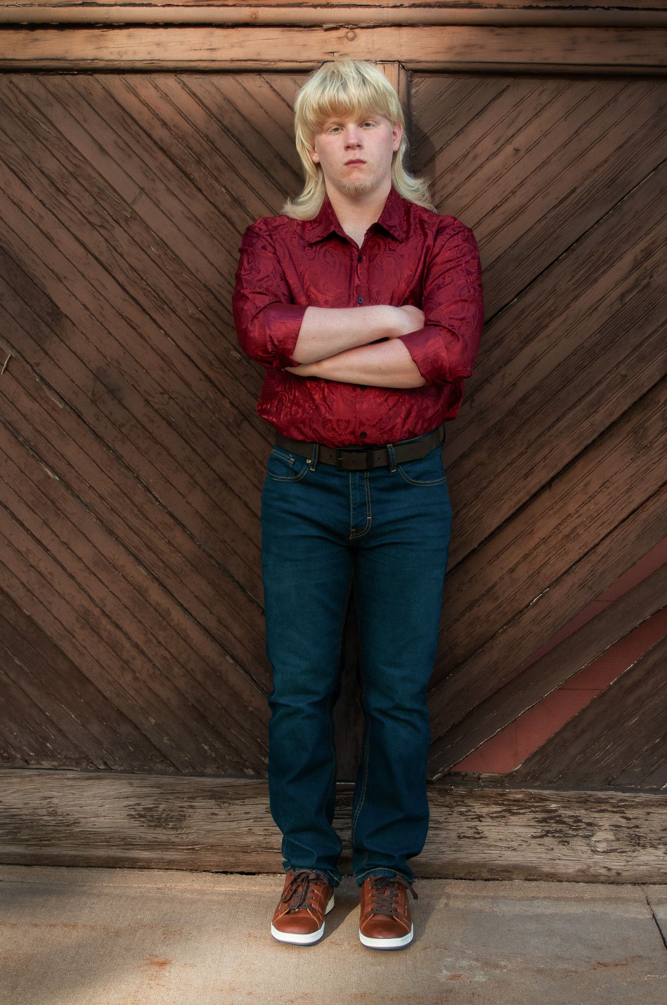 High school senior poses against a historic diagonal wooden plank door in Brewery District in Milwaukee, WI with Simply Junique