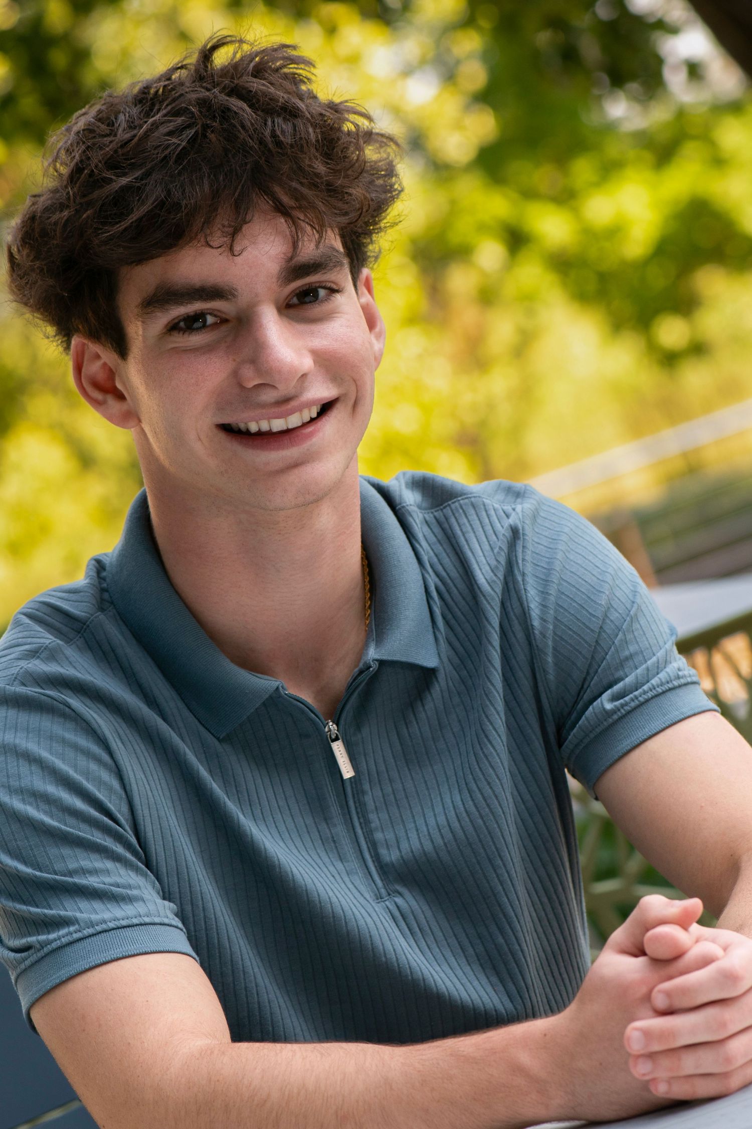 Casual outdoor portrait with golden bokeh background wearing a teal polo shirt at Northwestern Mutual, Franklin WI