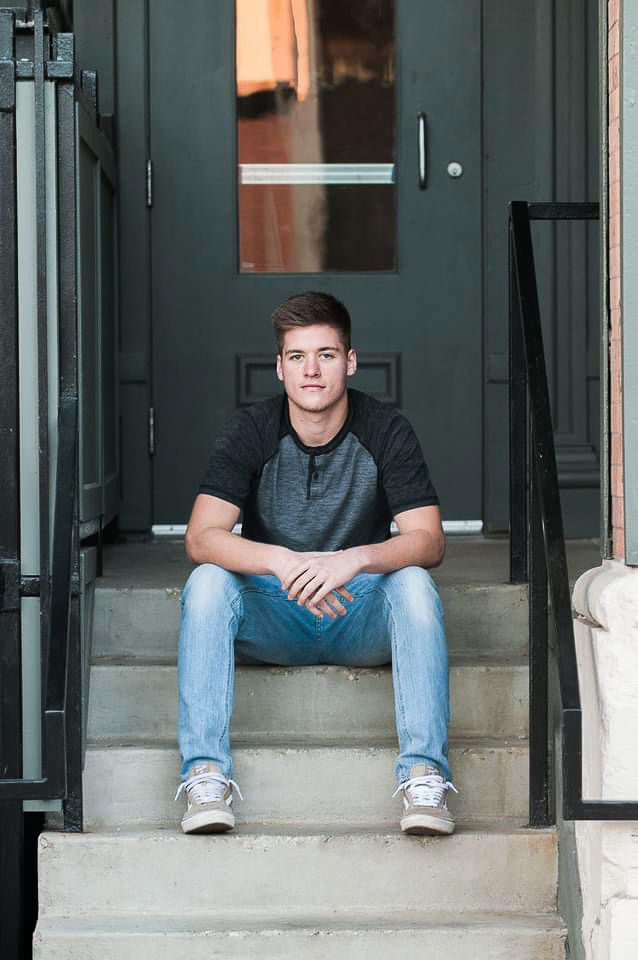 Casual portrait session on concrete steps with industrial green doors.