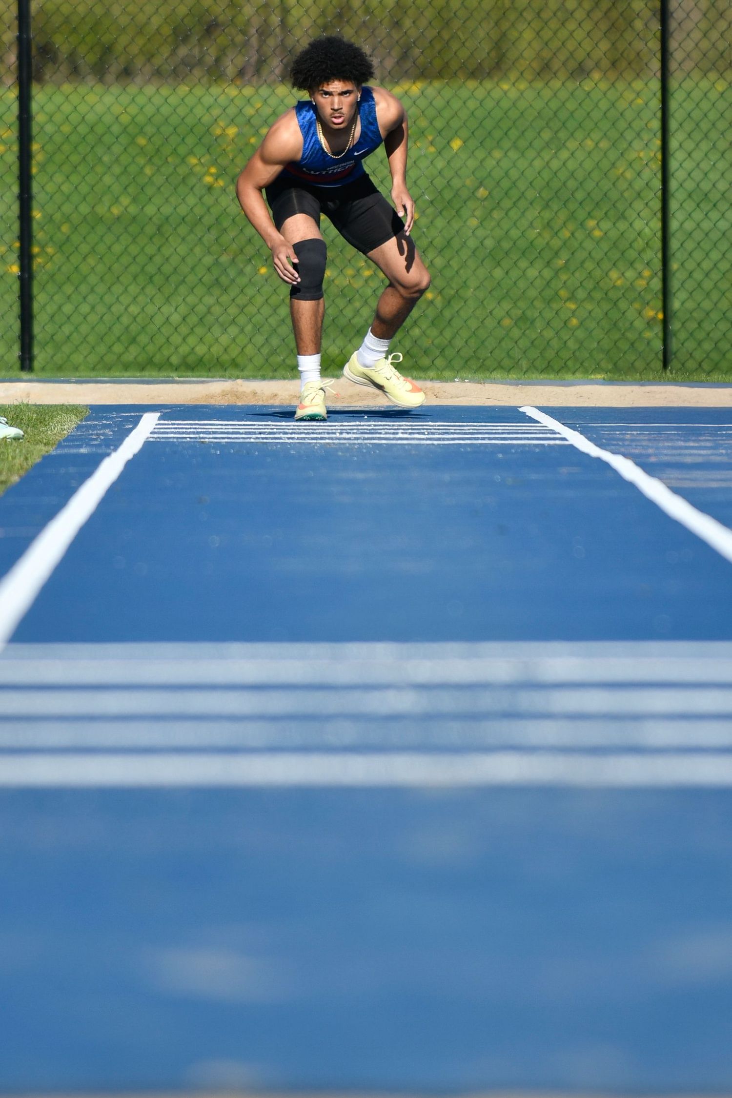 Athletes in starting positions on blue running track preparing to long jump. Game Day to Grad Day Senior Portrait Experience. Simply Junique