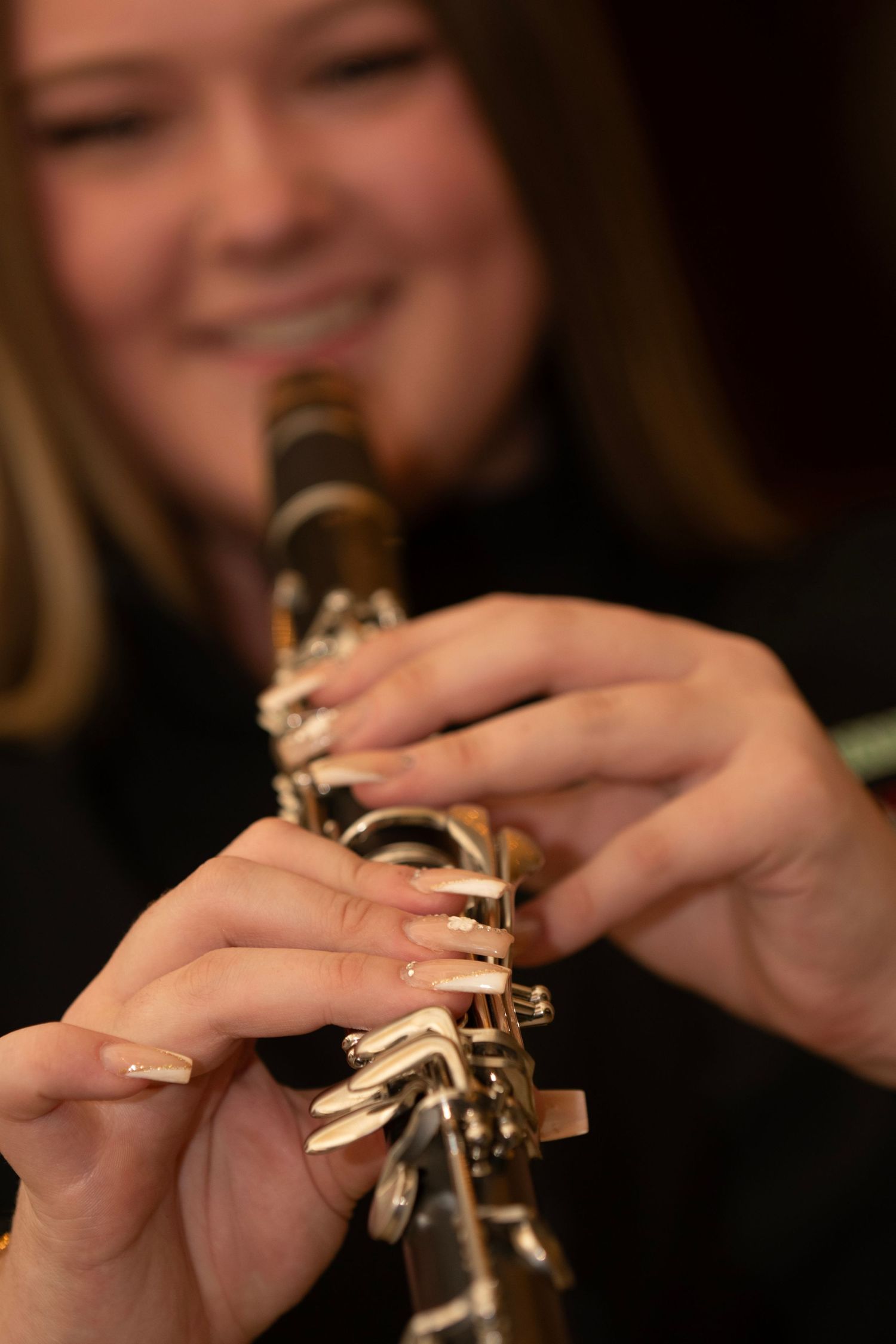 Close-up view of hands playing a trumpet with fingers positioned on the brass instrument's valves.