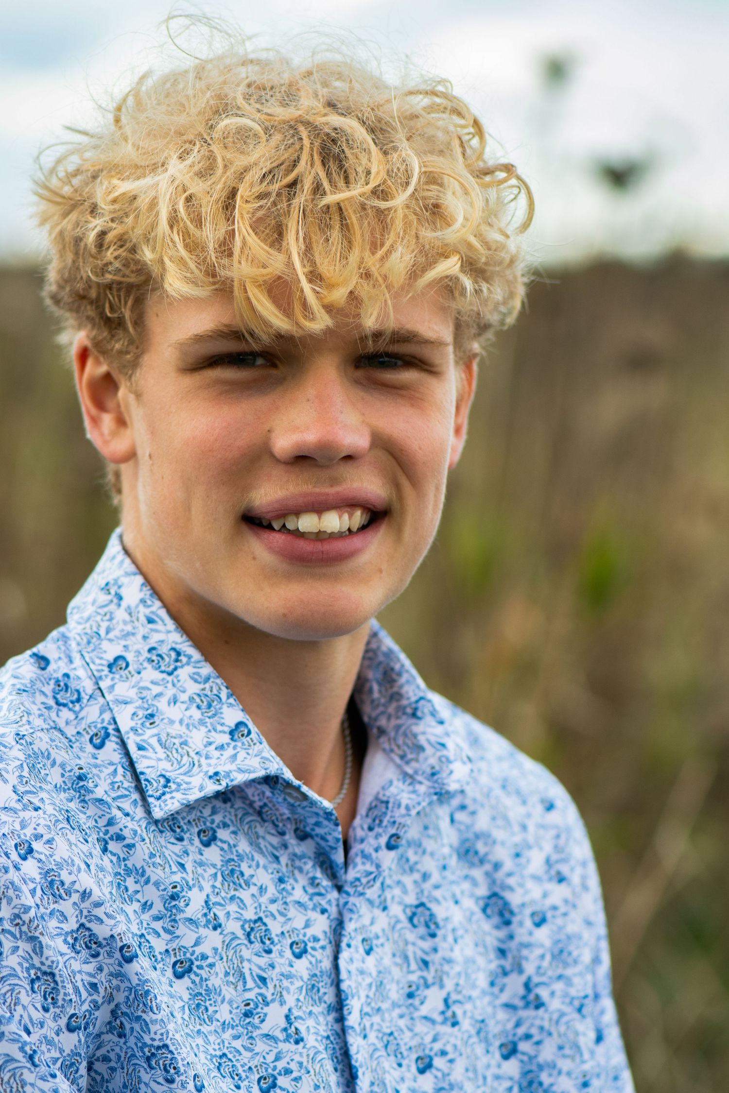 A close-up portrait shows someone wearing a light blue floral patterned shirt against a natural background. Milwaukee County Grounds