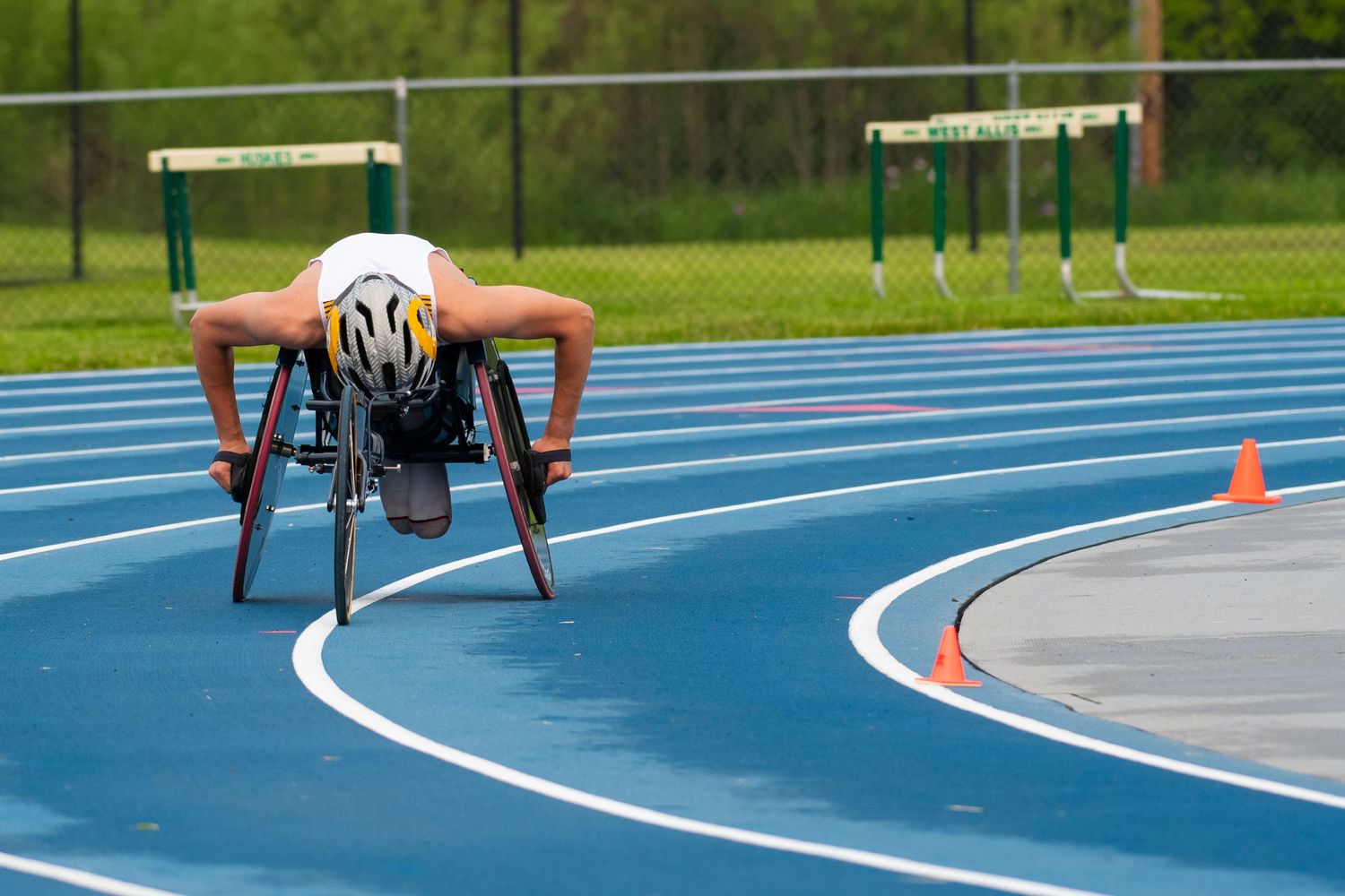 Athletes racing on a blue running track during an outdoor competition. Game Day to Grad Day Senior Portrait Experience. Simply Junique