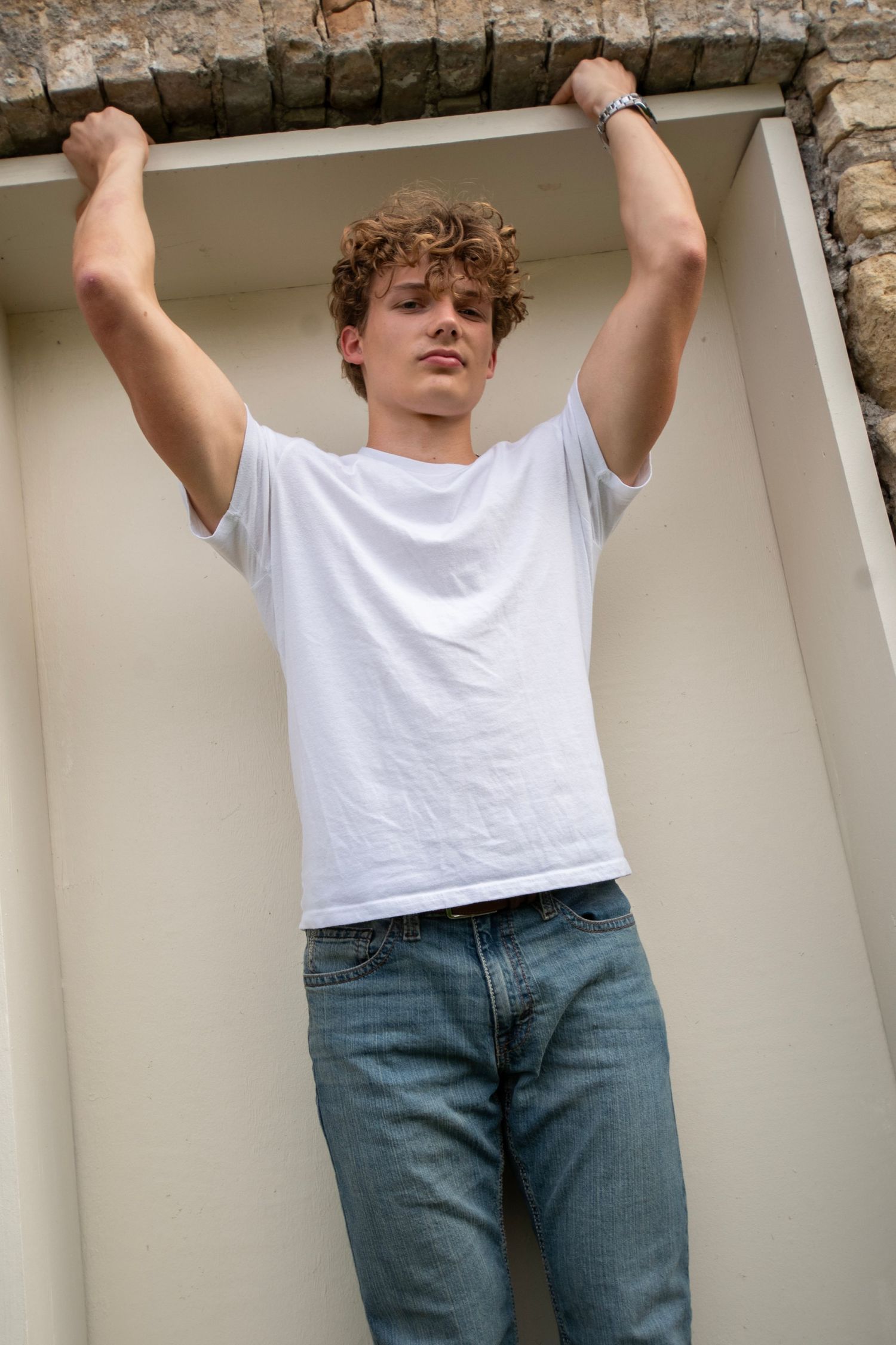 Person in white t-shirt and jeans shown in a sequence of poses against white columns outdoors.
