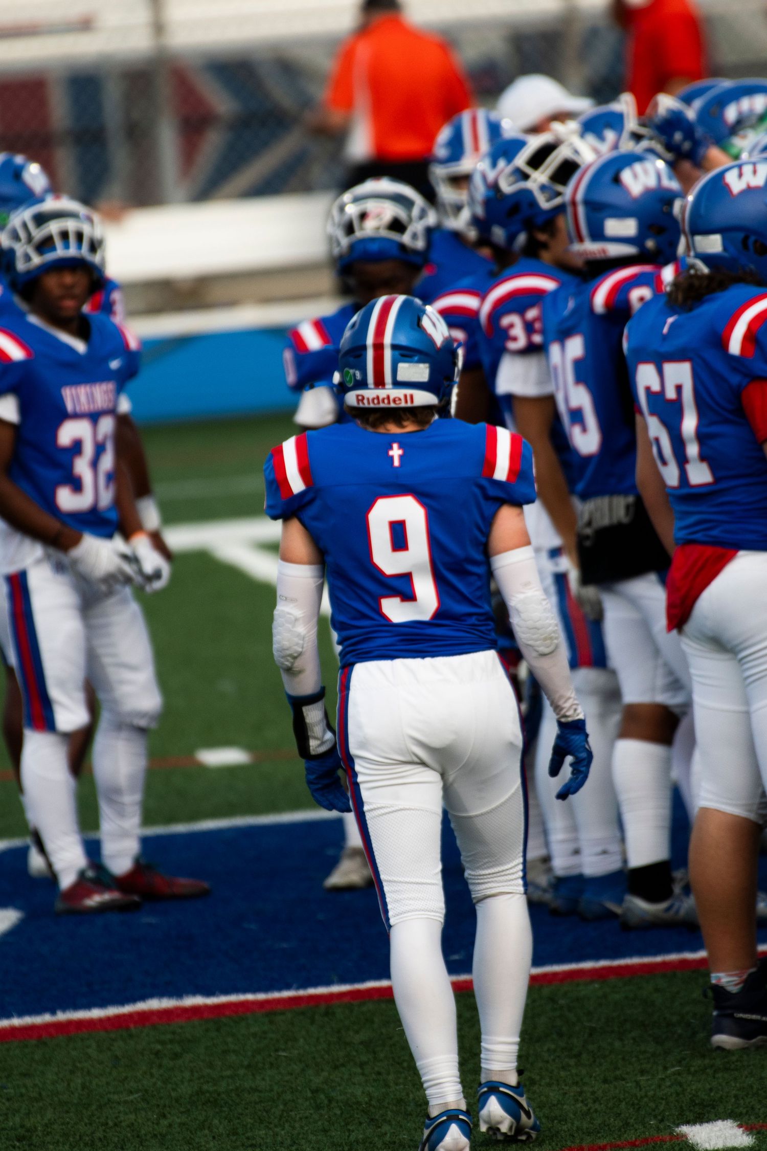 Football players in blue and white uniforms with number 9 jersey visible on field during game day.