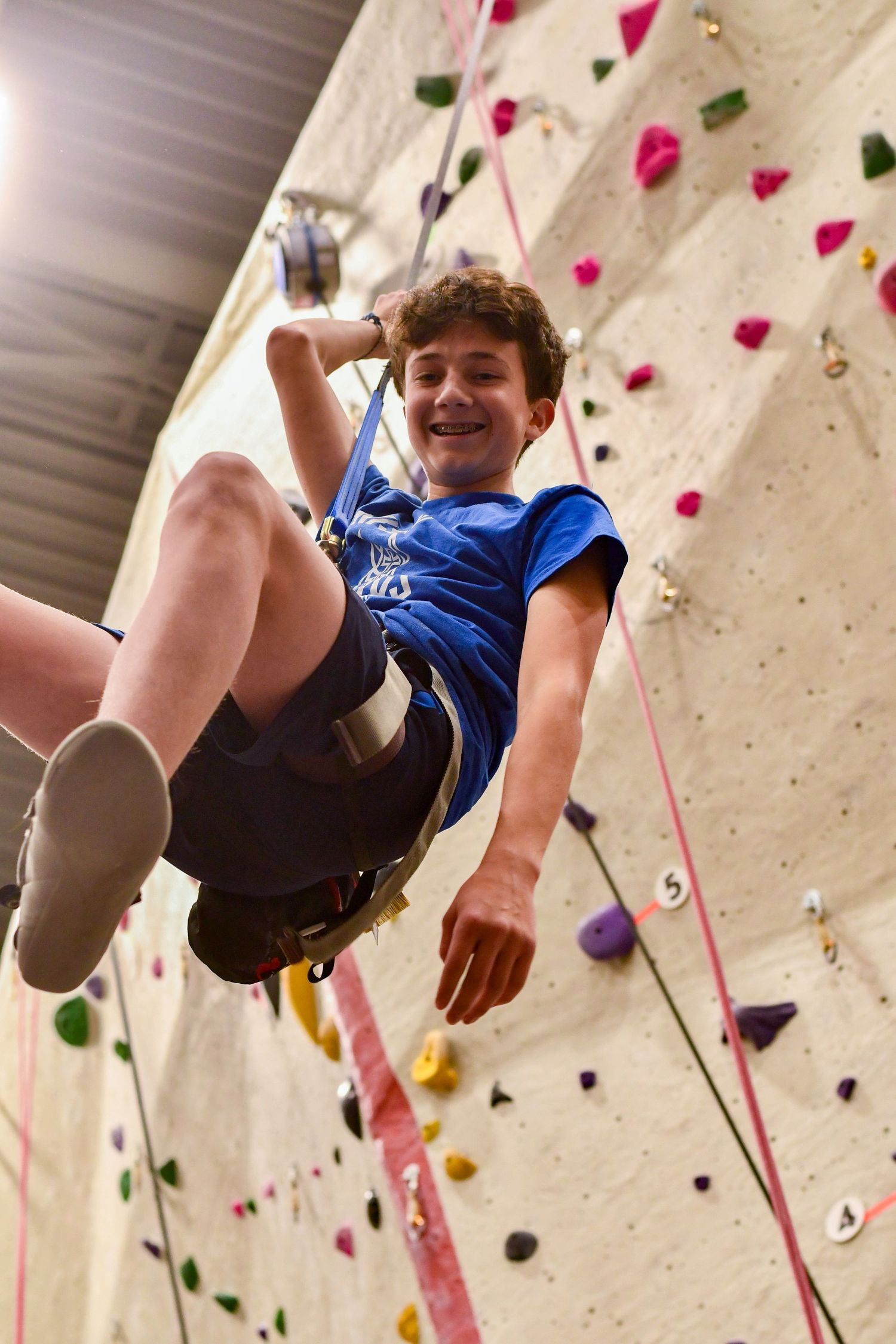Rock climber scaling an indoor climbing wall with colorful holds.