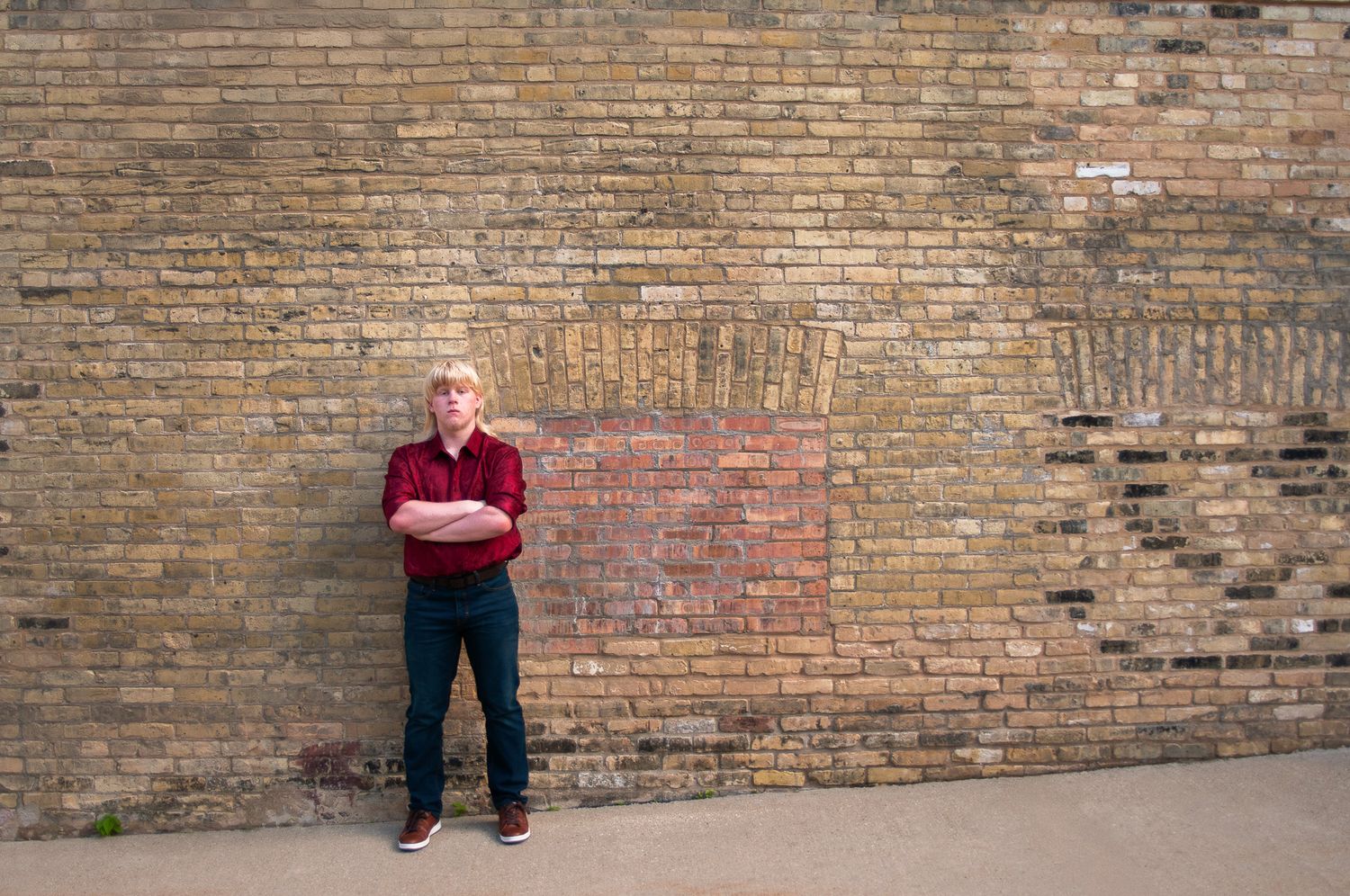 High school senior poses against a cream city brick wall backdrop near Pabst Brewery in Milwaukee's brewery district with Simply Junique.