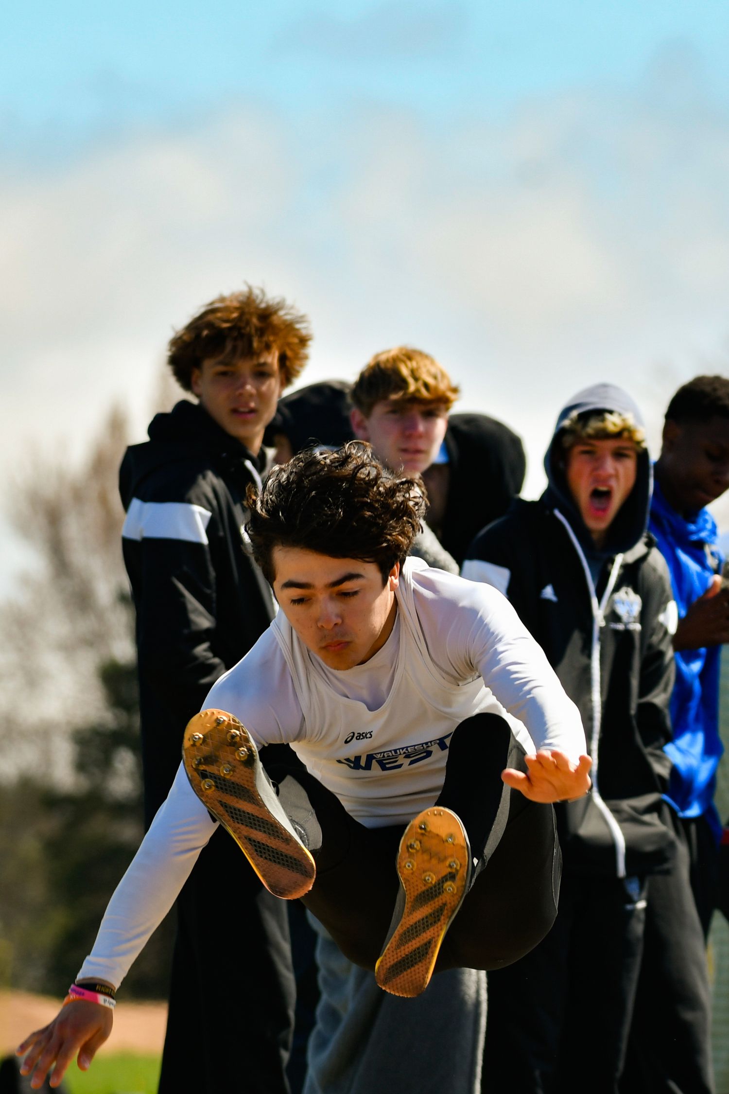 Athletes warming up before a track meet with energetic jumping exercises.