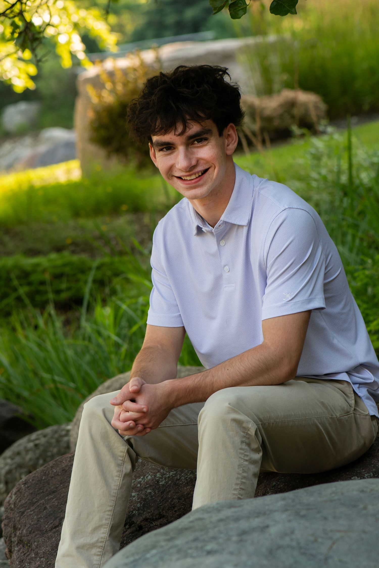 Natural outdoor senior photos on rocky terrain wearing white polo and khaki pants at Northwestern Mutual, Franklin WI