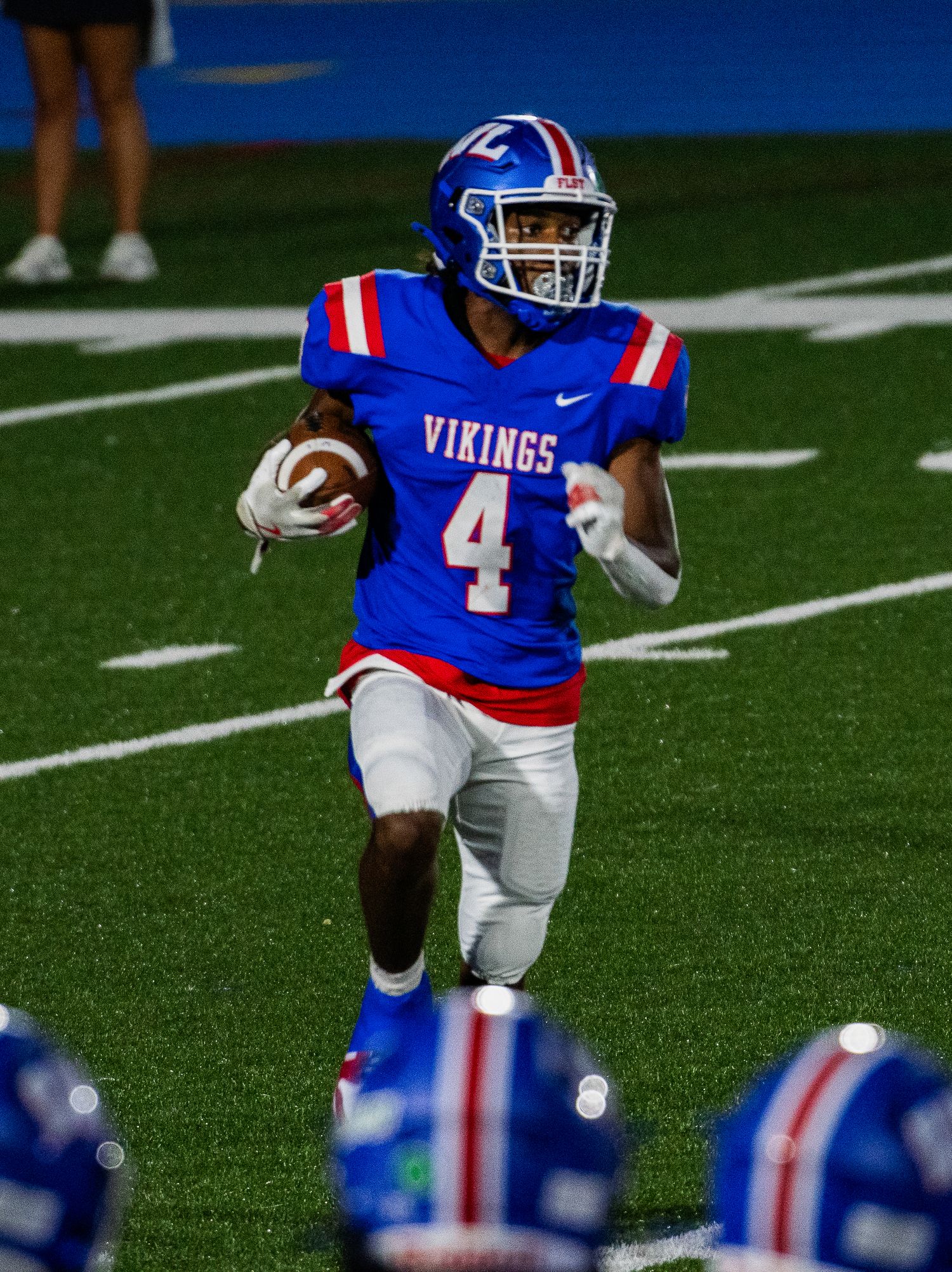 Football player in blue and white Wisconsin Lutheran Vikings uniform running with ball on field. Game Day to Grad Day Senior Portraits