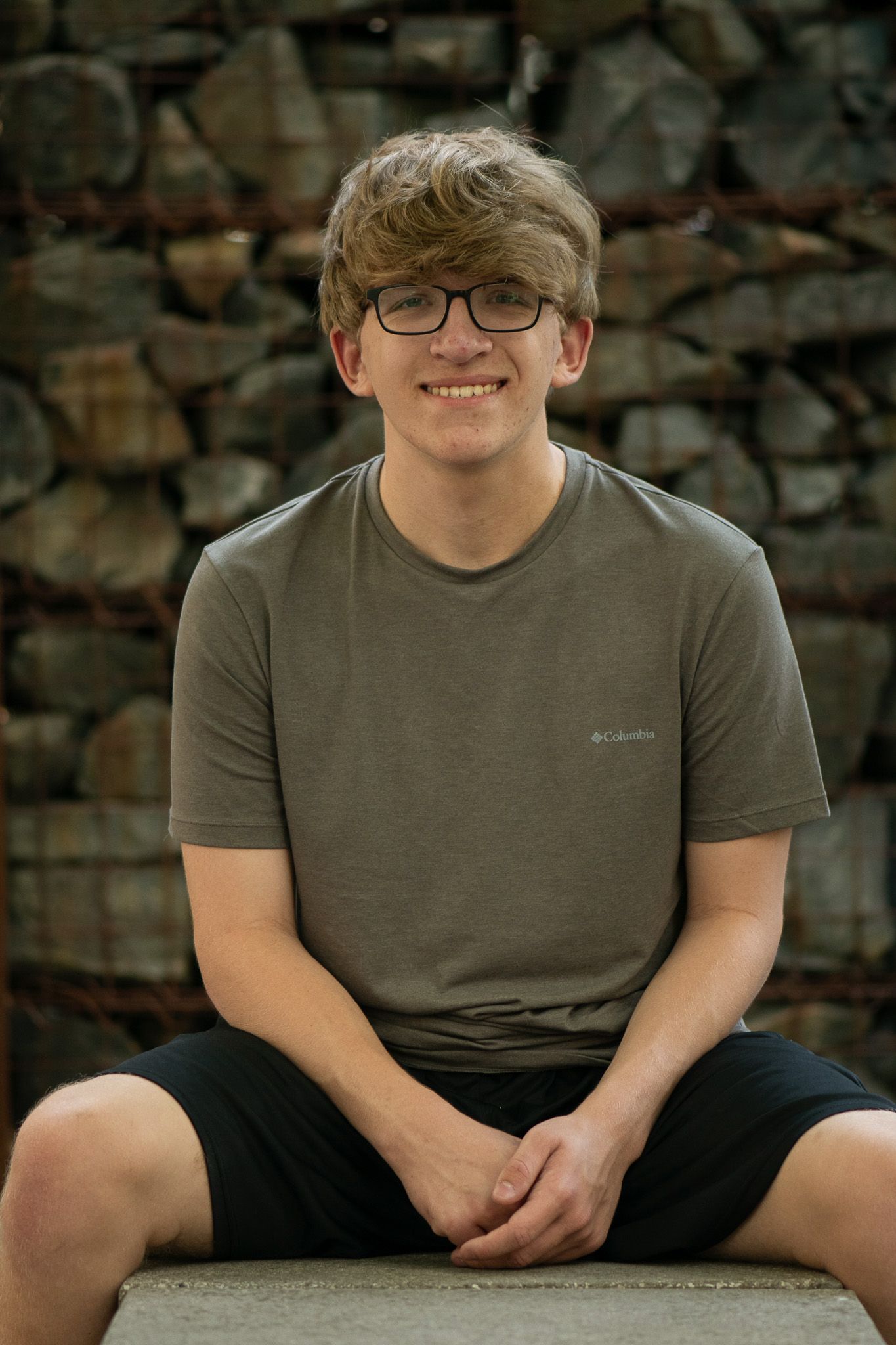 Outdoor portraits against a rustic stone wall background for senior portrait session in Milwaukee, WI.
