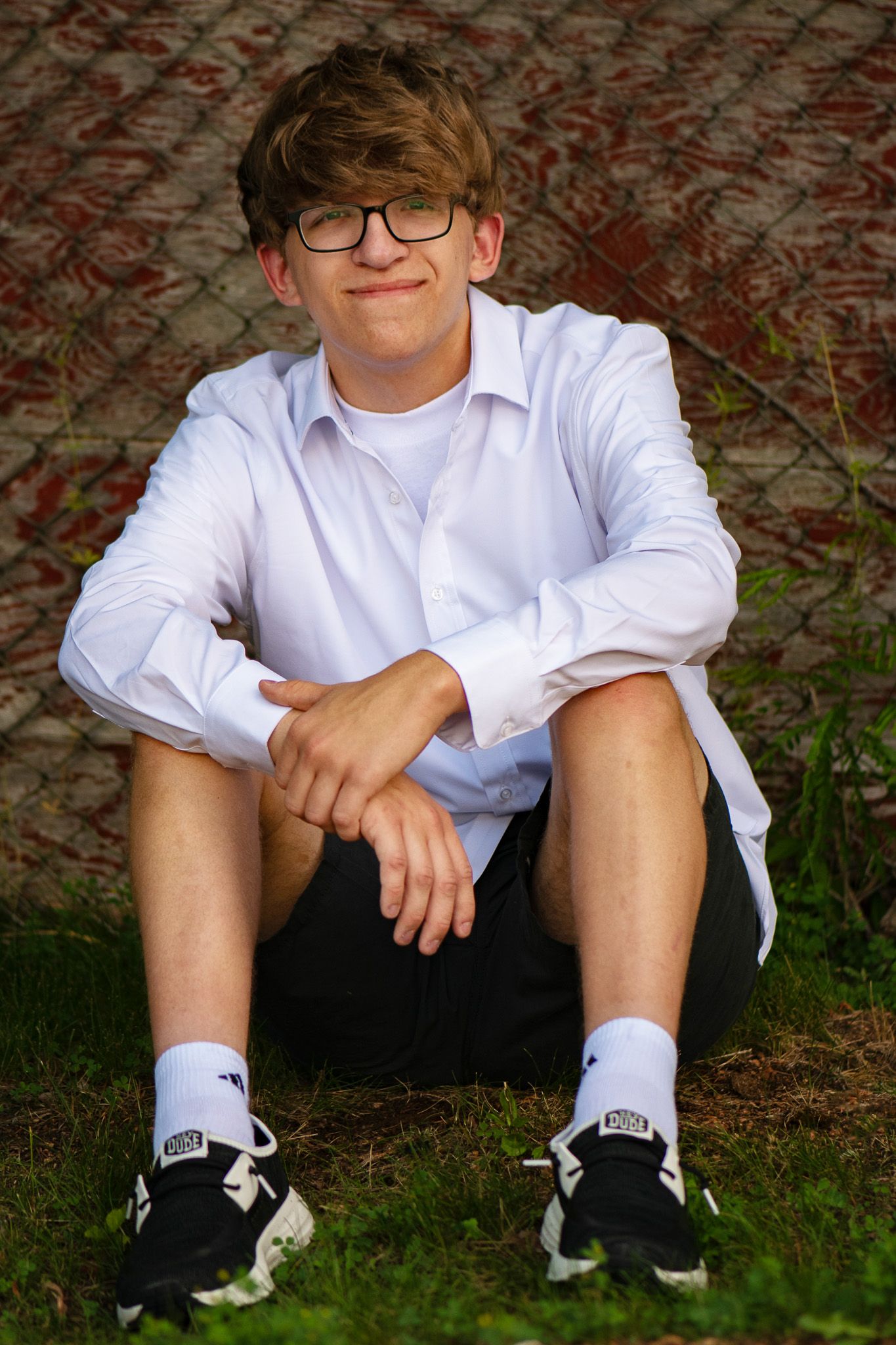 A casual outdoor portrait with Greenfield, WI high school senior sitting on grass.