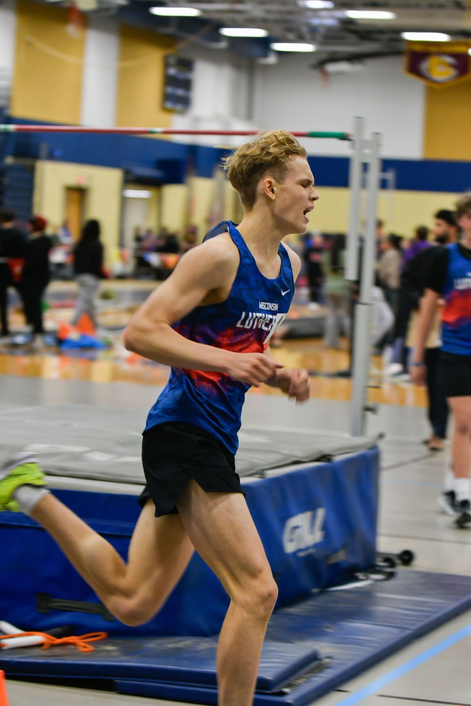Athlete in blue uniform practicing running in indoor facility. Game Day to Grad Day Senior Portrait Experience with Simply Junique