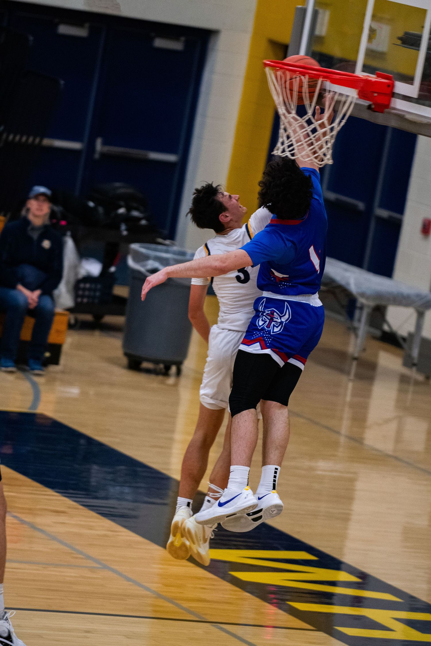 Basketball players jumping for a layup during indoor game on court.