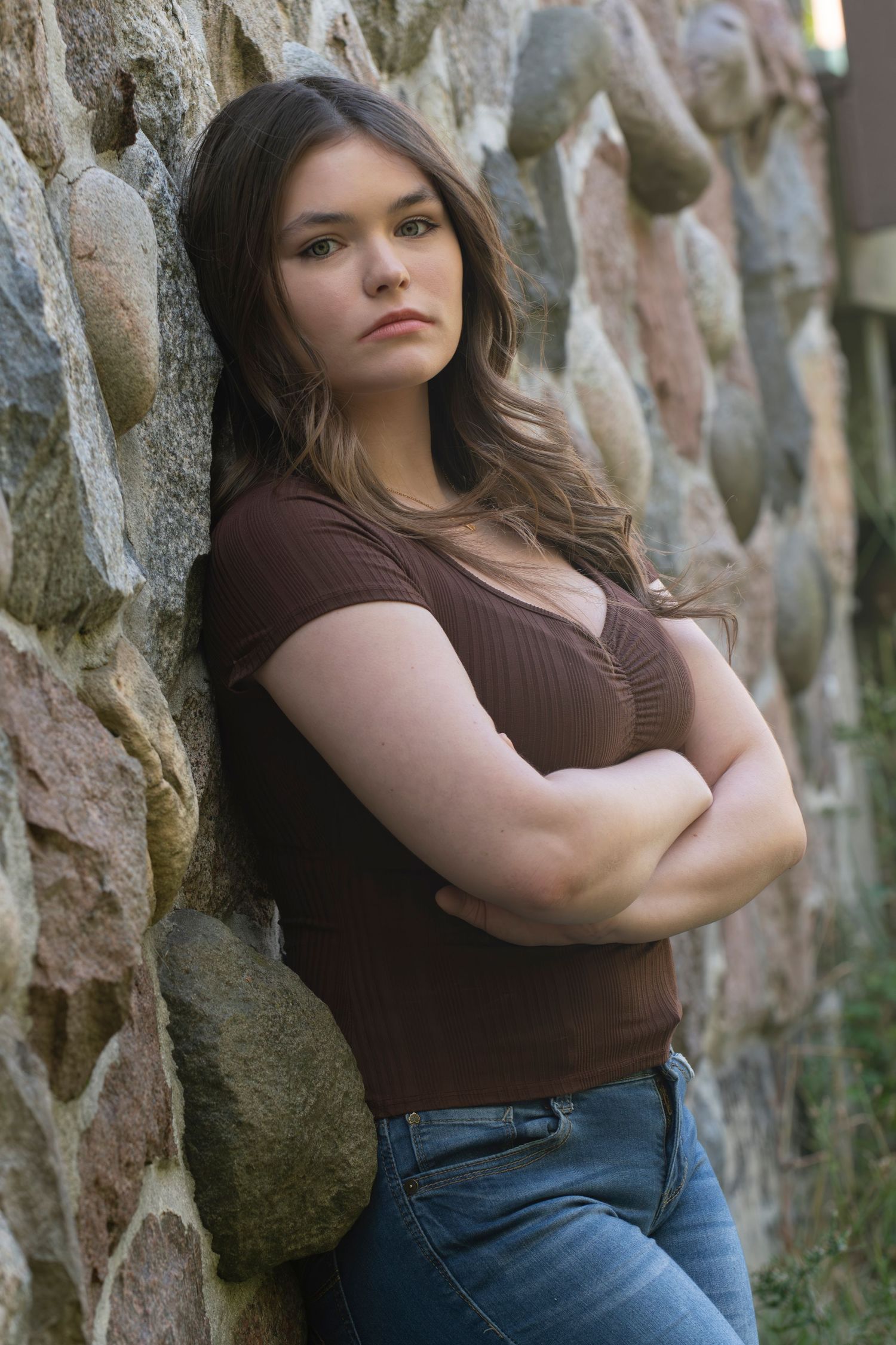 High school senior poses against rustic stone wall in the Kettle Moraine State Park in Delafield, WI for her Simply Junique Portrait Session