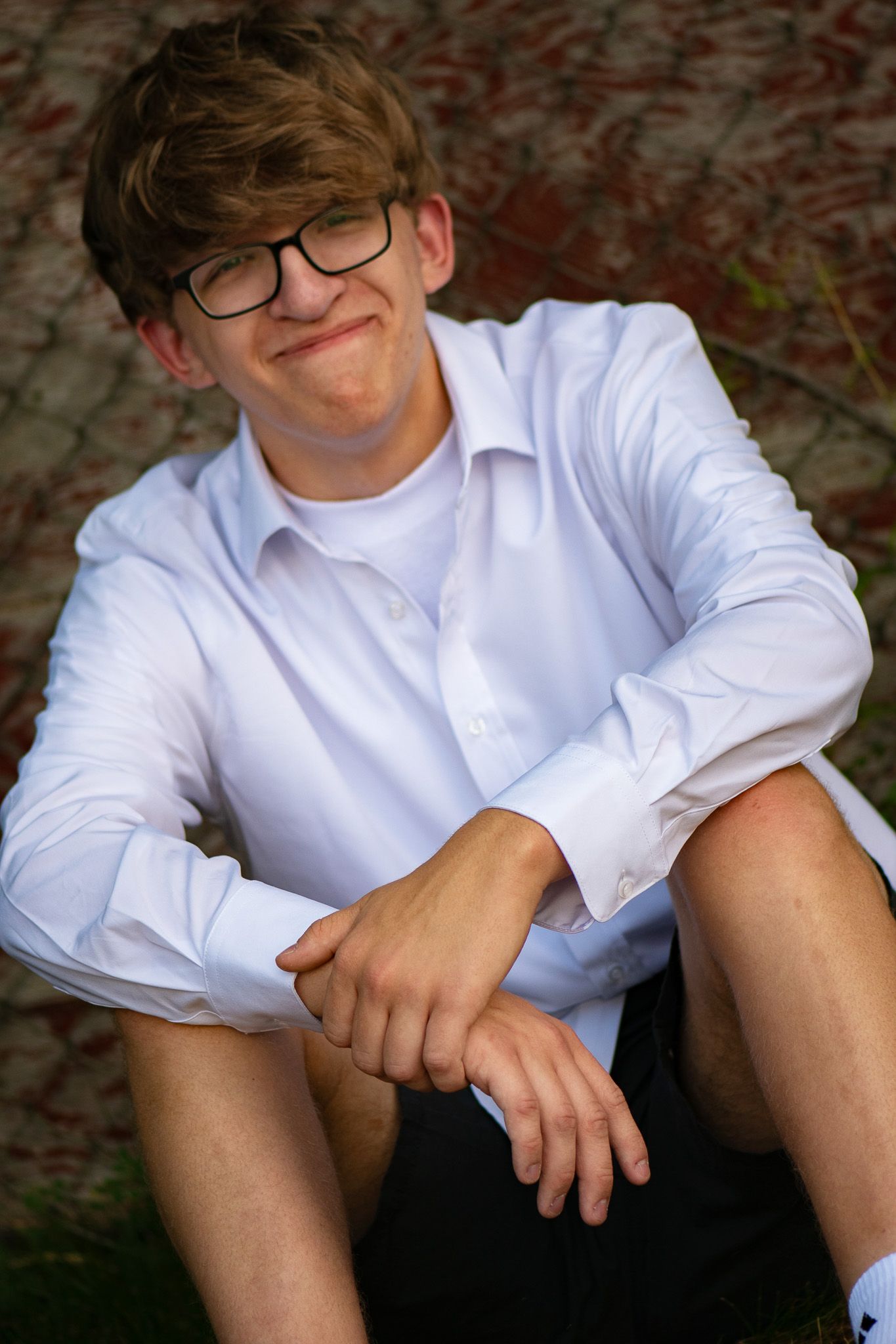 A casual outdoor portrait with Greenfield, WI high school senior sitting on grass.