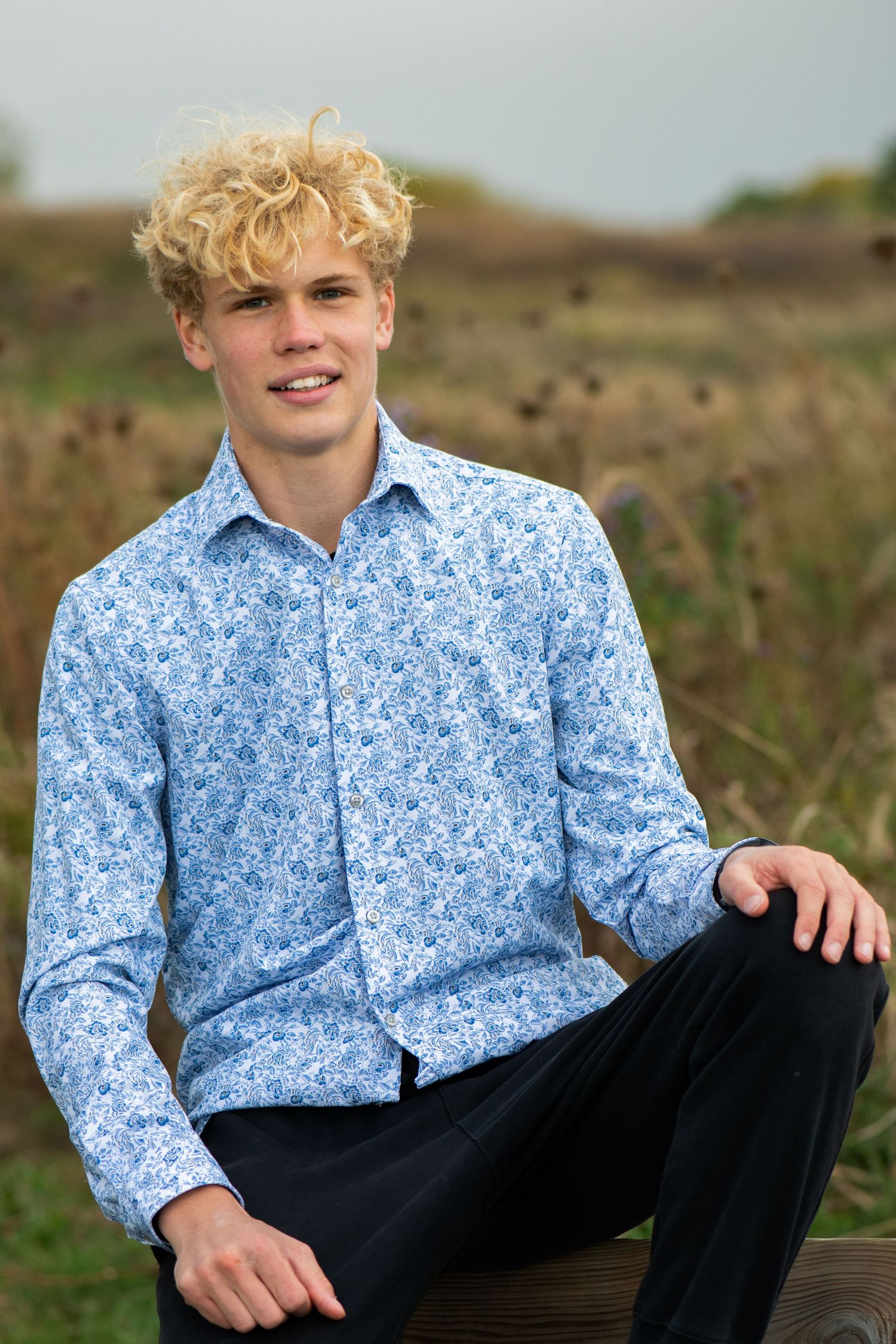 Person in light blue floral button-down shirt and dark pants poses casually outdoors. Milwaukee County Grounds Simply Junique Portraits