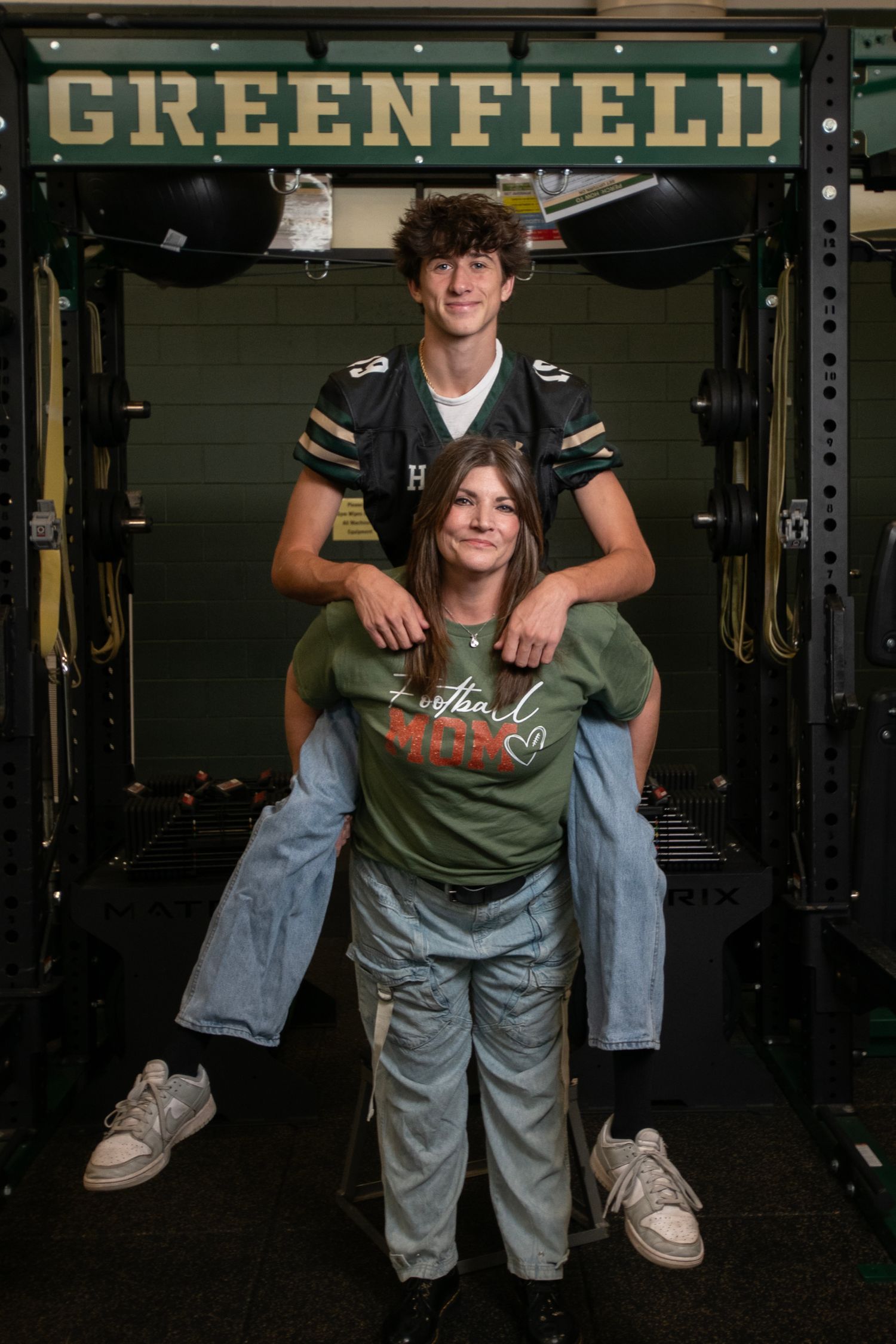 Three similar photos show people posing in a dark gym setting with Greenfield signage visible in the background.