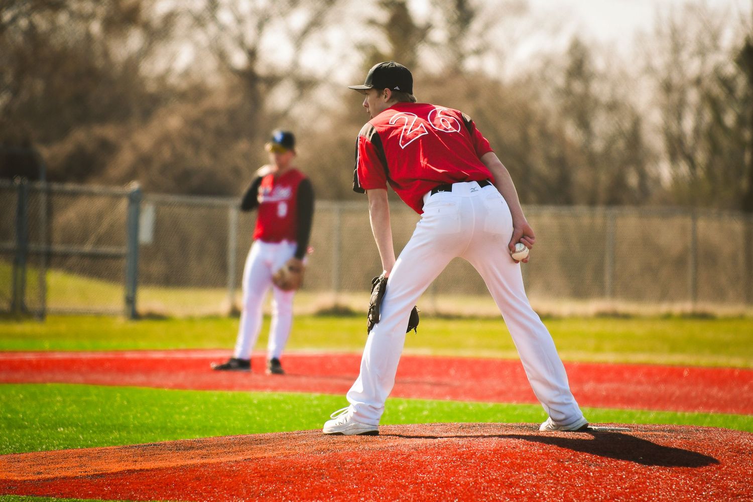 Baseball players on red turf baseball field during practice. Game Day to Grad Day Senior Portrait Experience. Simply Junique