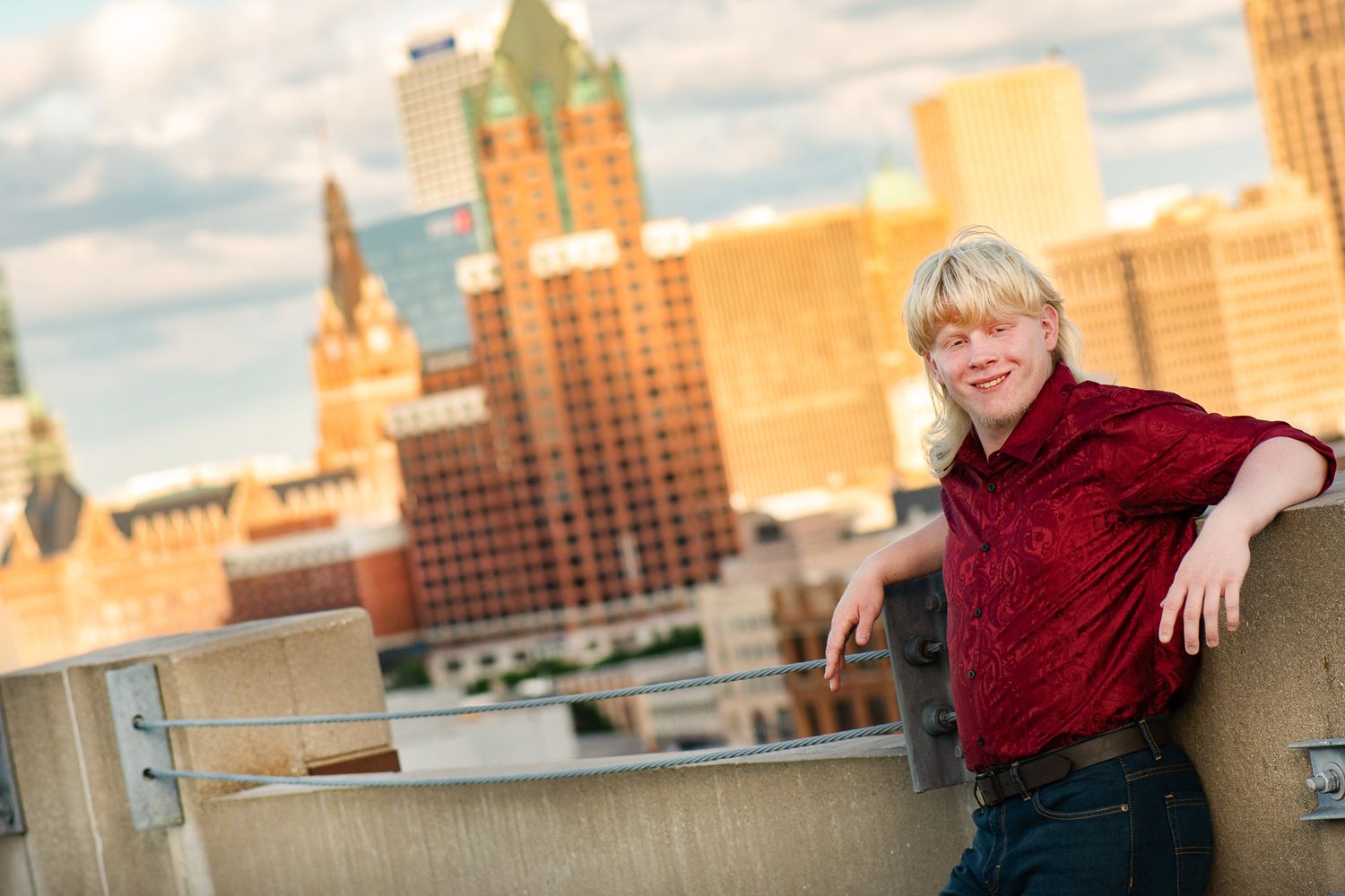 High school senior poses in an urban setting with the city of milwaukee skyline as the backdrop for a Simply Junique portrait session.