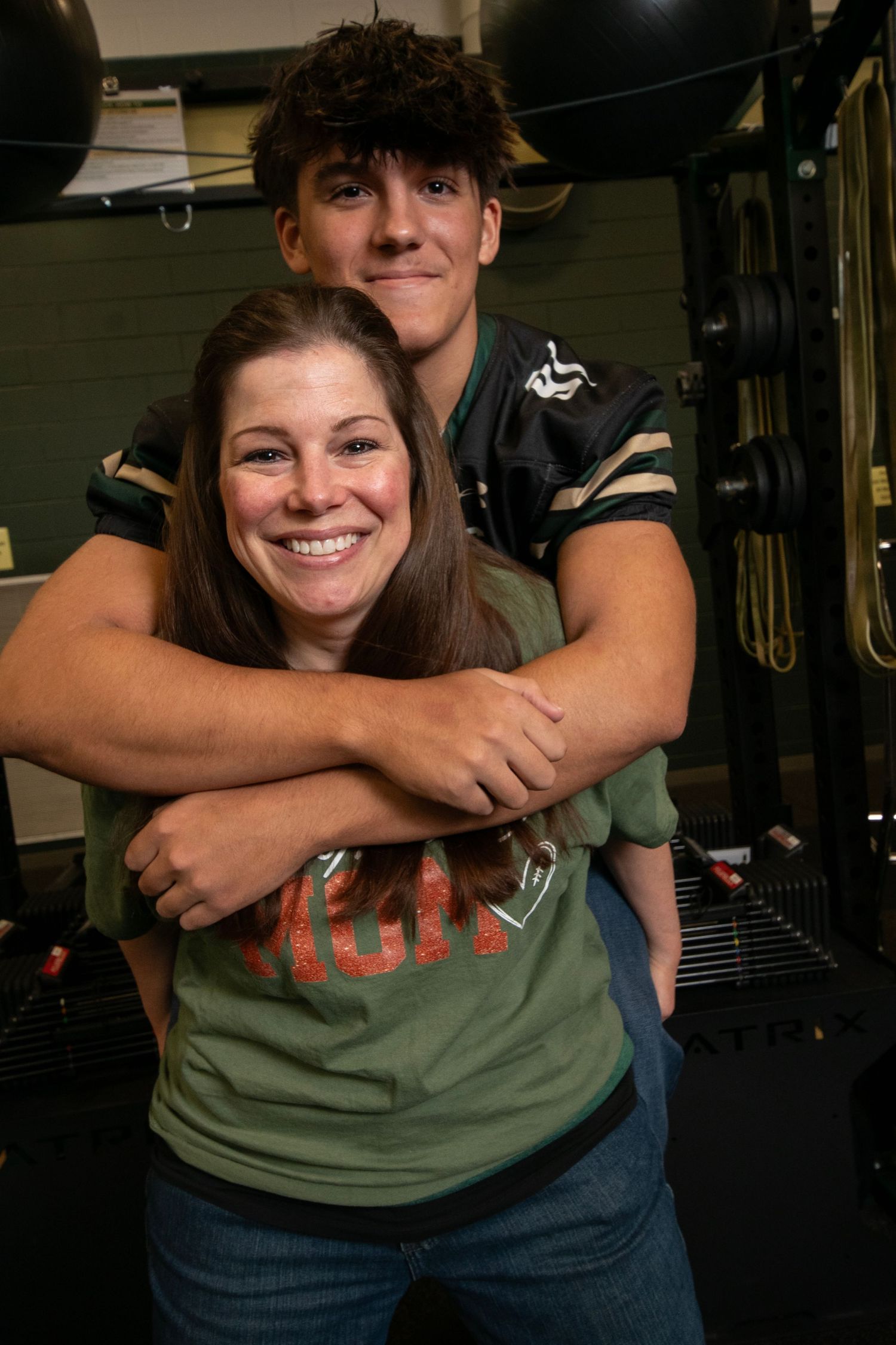 A sequence of photos showing a playful hug from behind in a dimly lit gym setting.