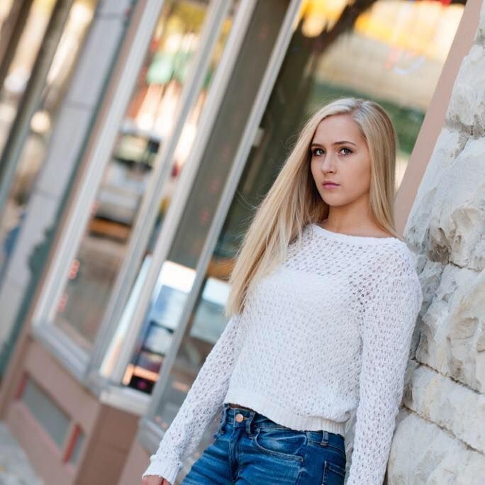 Classic high school senior portrait in white crochet sweater and jeans against textured wall during sunset Waukesha, WI with Simply Junique