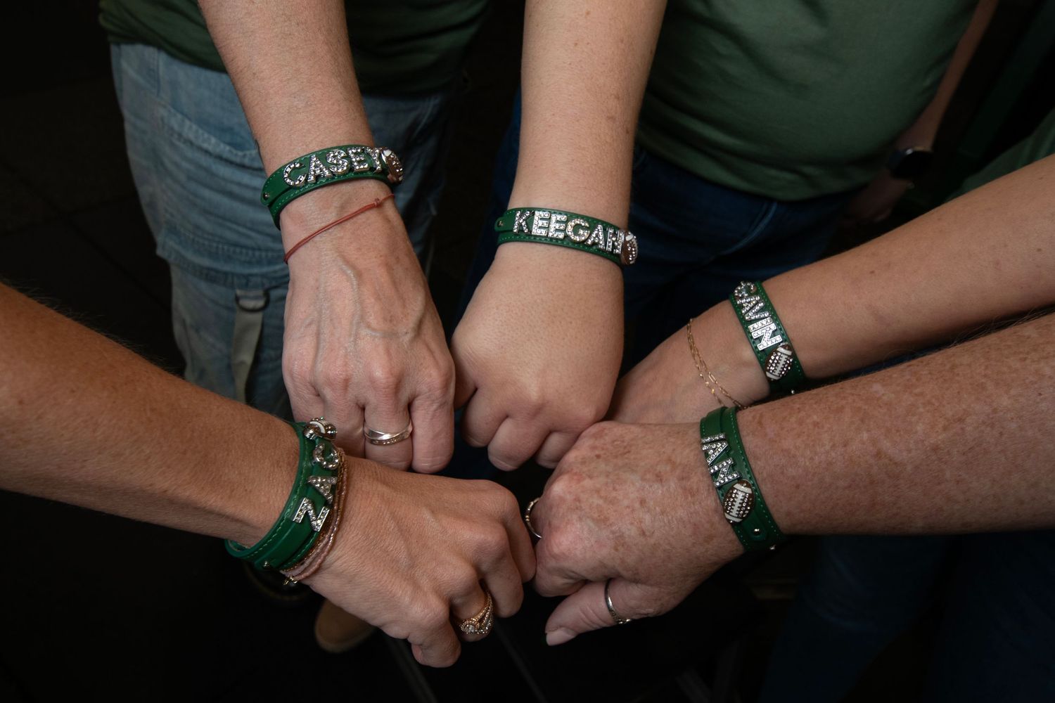A sequence of close-up shots showing hands wearing green silicone wristbands from different angles.