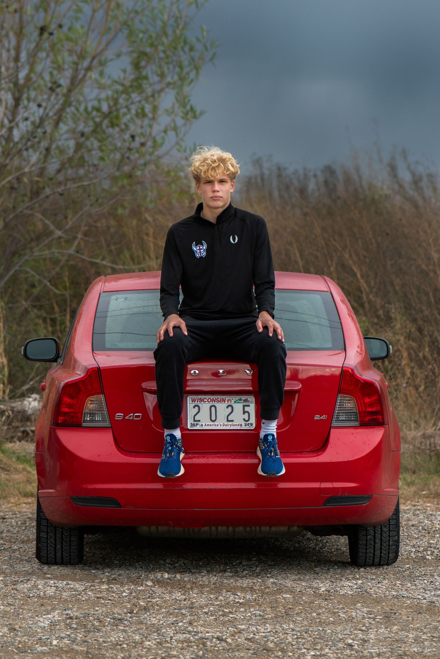 Person sitting on trunk of red sports car wearing casual athletic wear and blue sneakers. Milwaukee County Grounds Simply Junique Portraits