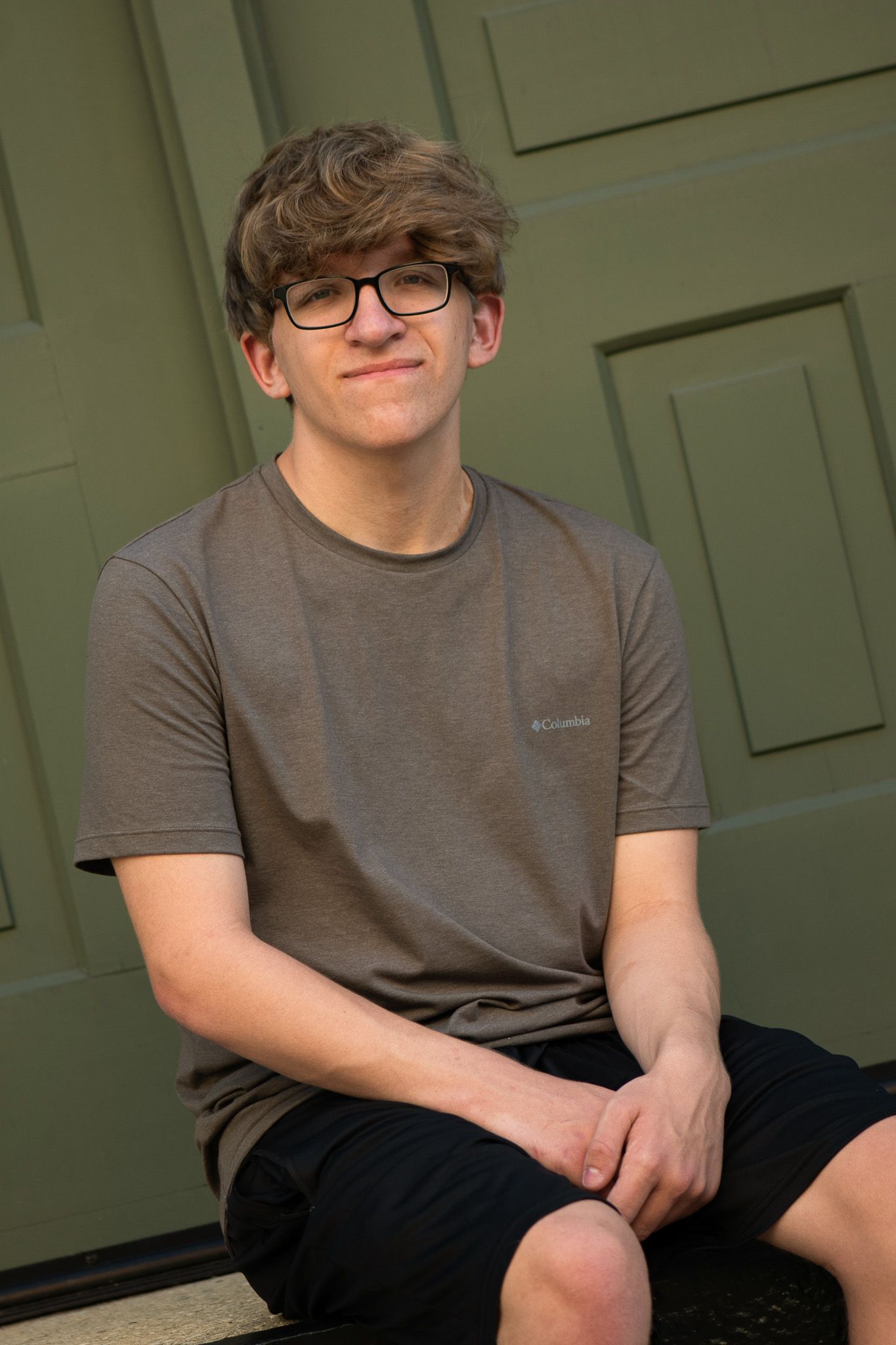 Casual portraits in front of a green paneled door for senior portrait session with Simply Junique in Milwaukee, WI