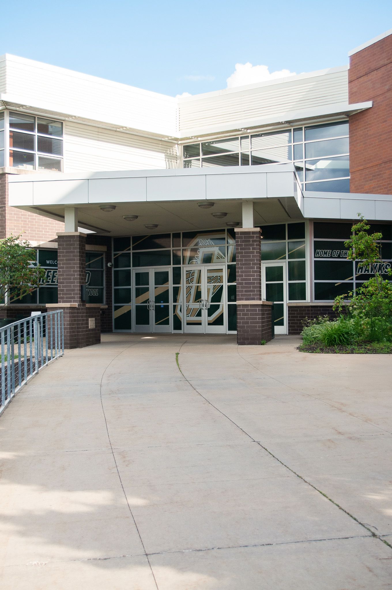Modern school building exterior with covered walkway and brick facade.