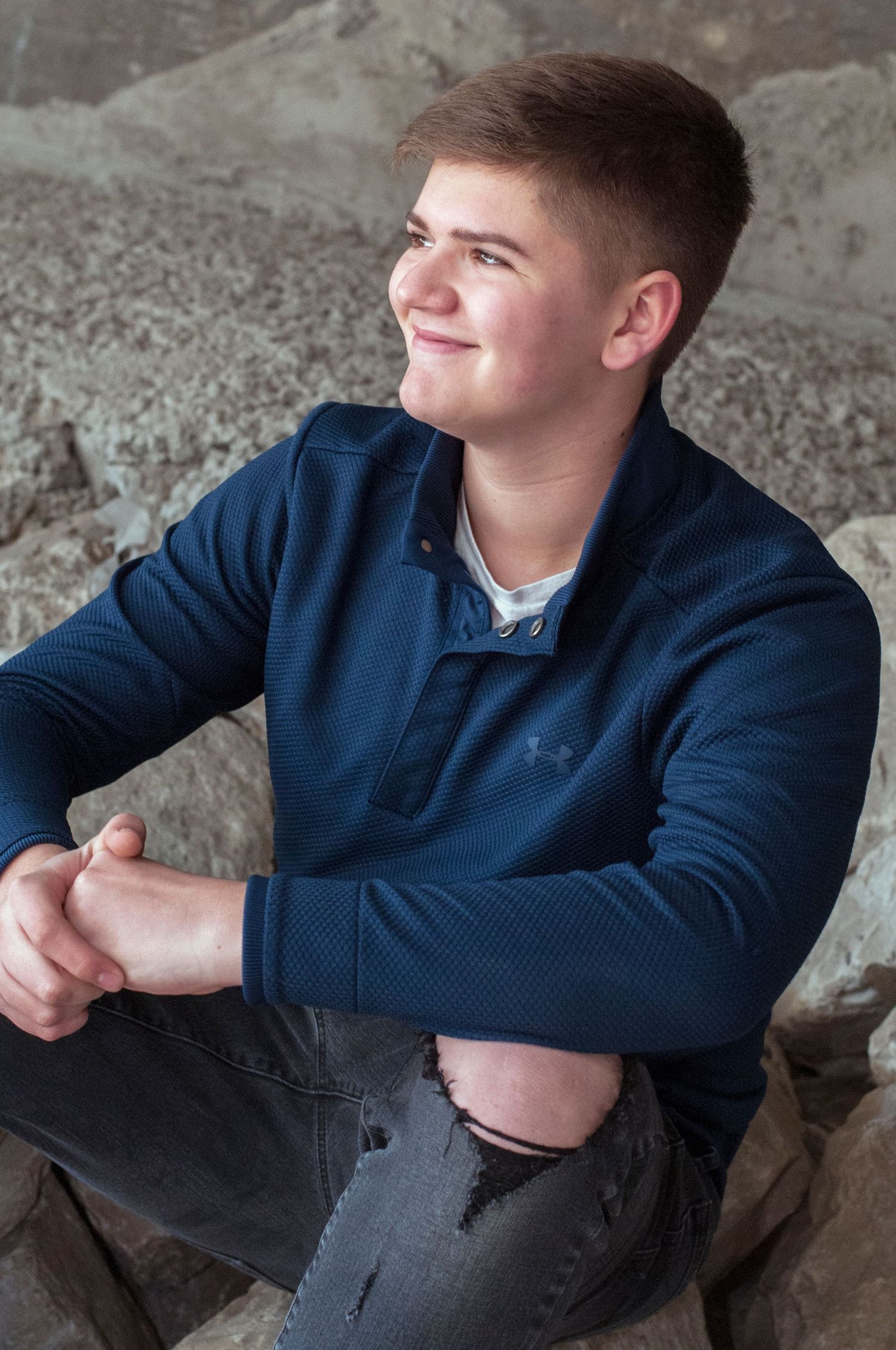 Series of casual poses in a navy sweater against a concrete wall background.