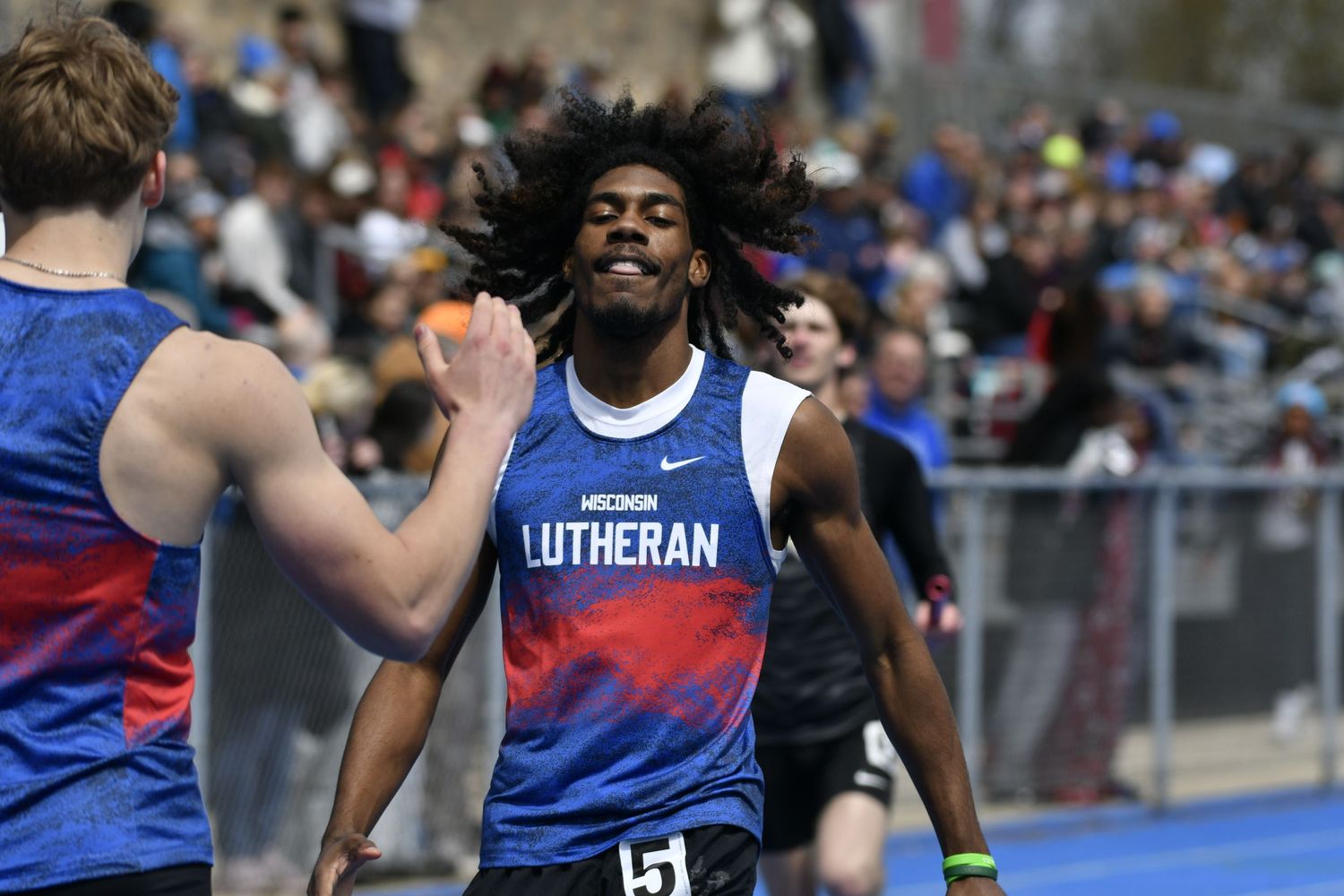 Track athletes competing in a race wearing blue and white uniforms.
