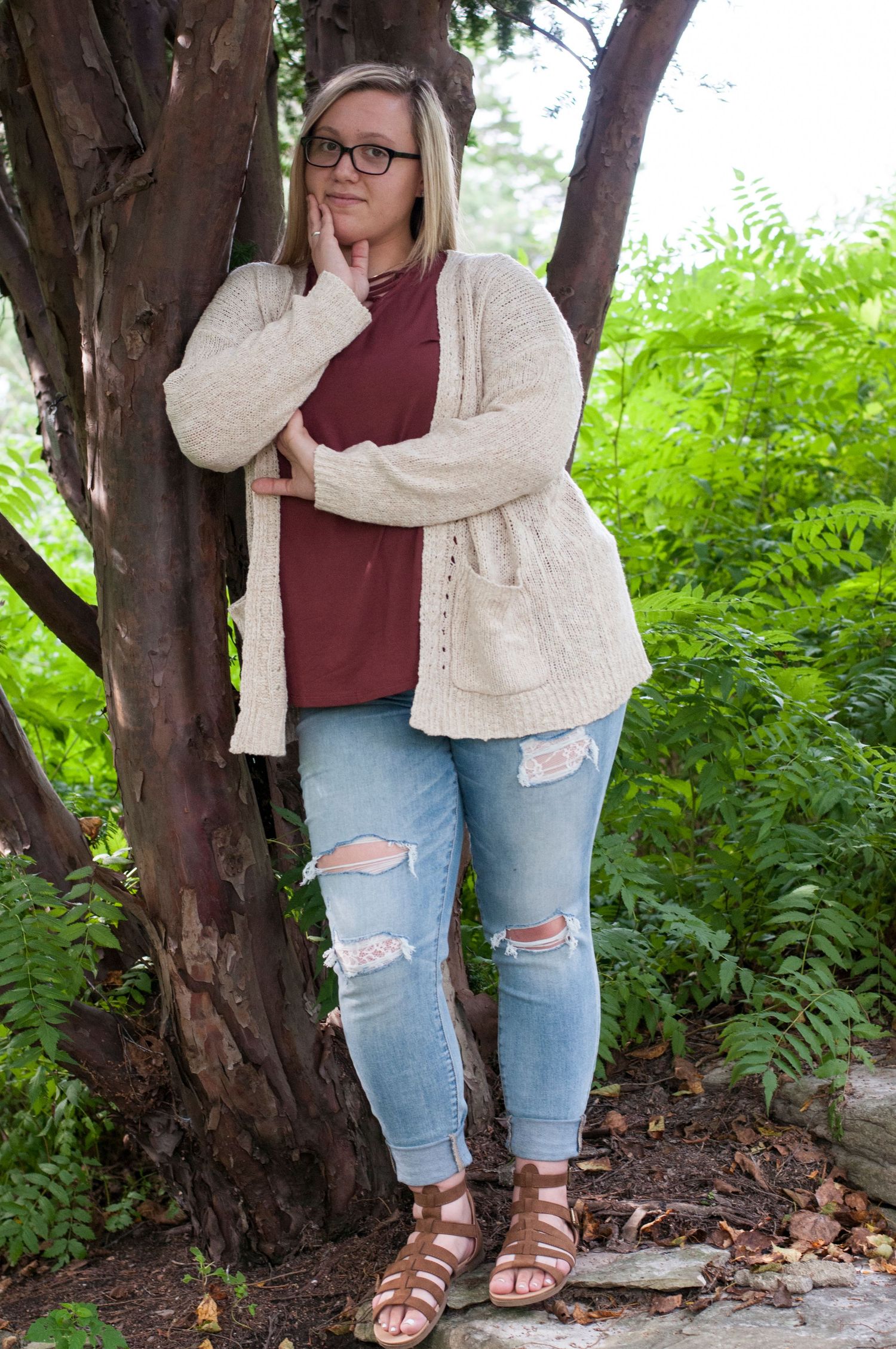 Casual outdoor portraits against tree trunks wearing distressed jeans and cream cardigan.