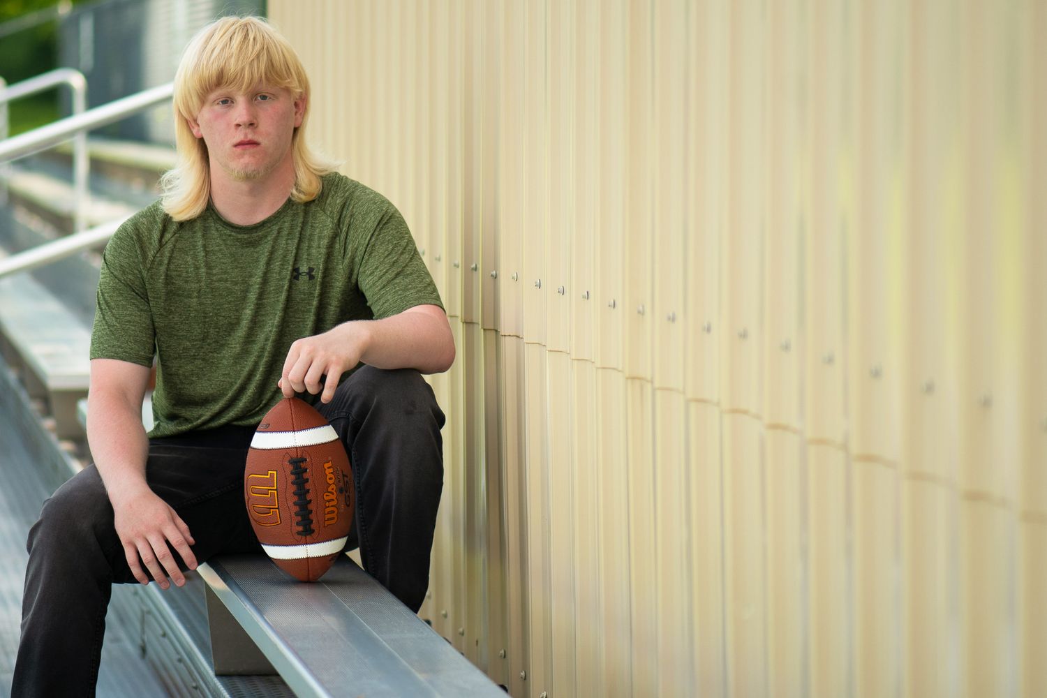 Casual portrait set against yellow siding with football as prop.