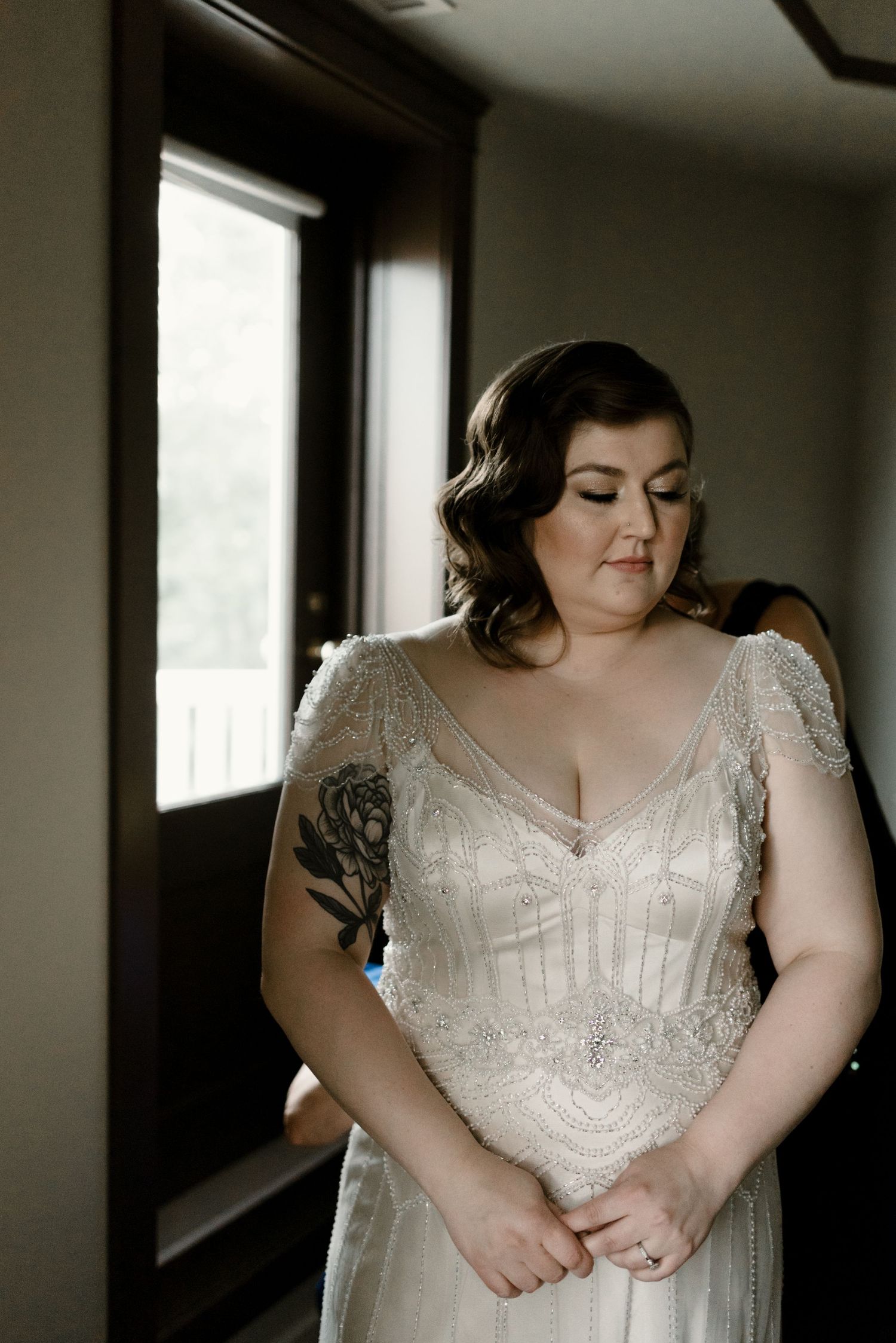 Close-up details of an intricate beaded white wedding dress bodice in natural window light.