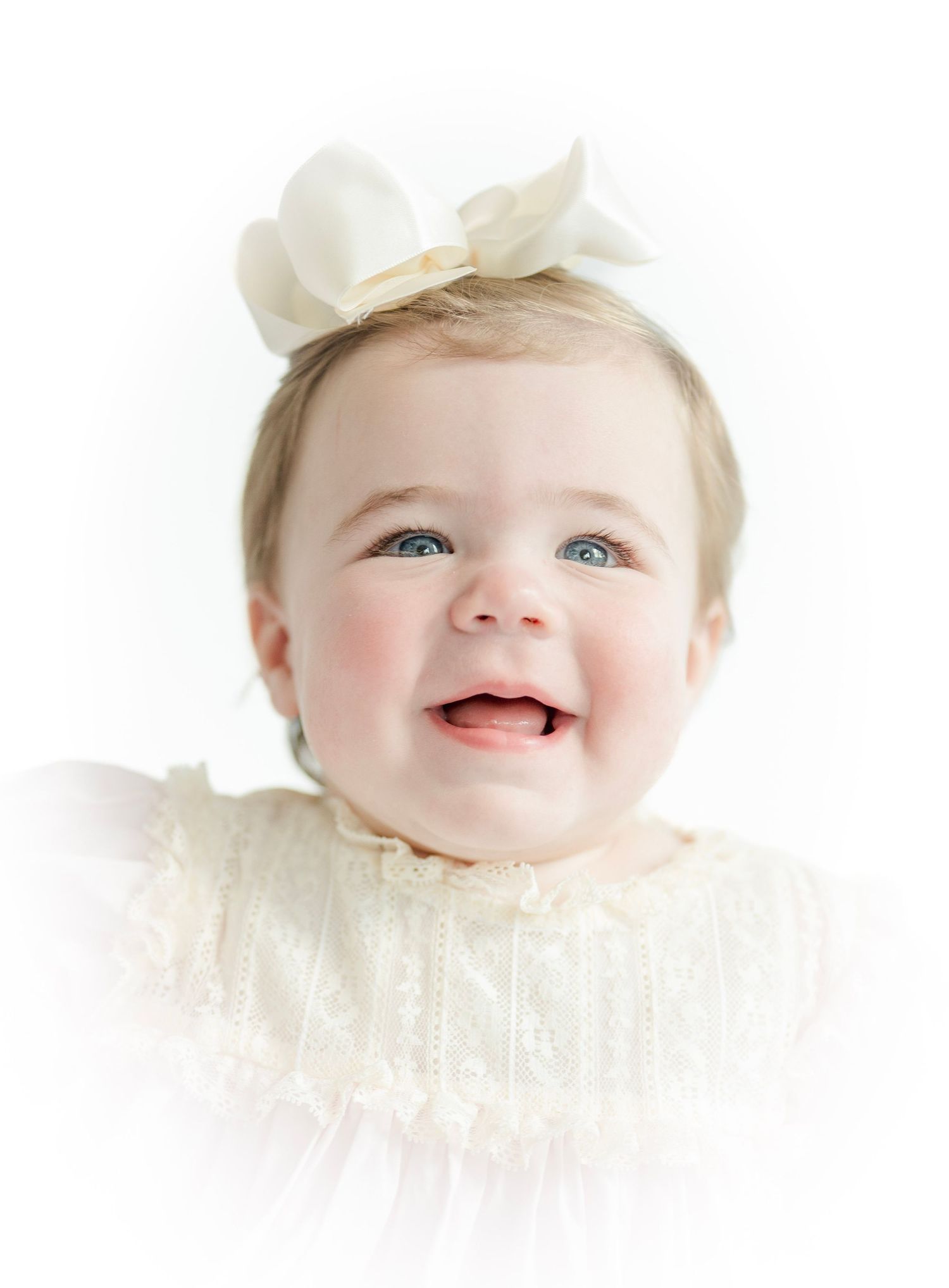 Sweet baby portraits showing joyful expressions wearing white lace against bright background.