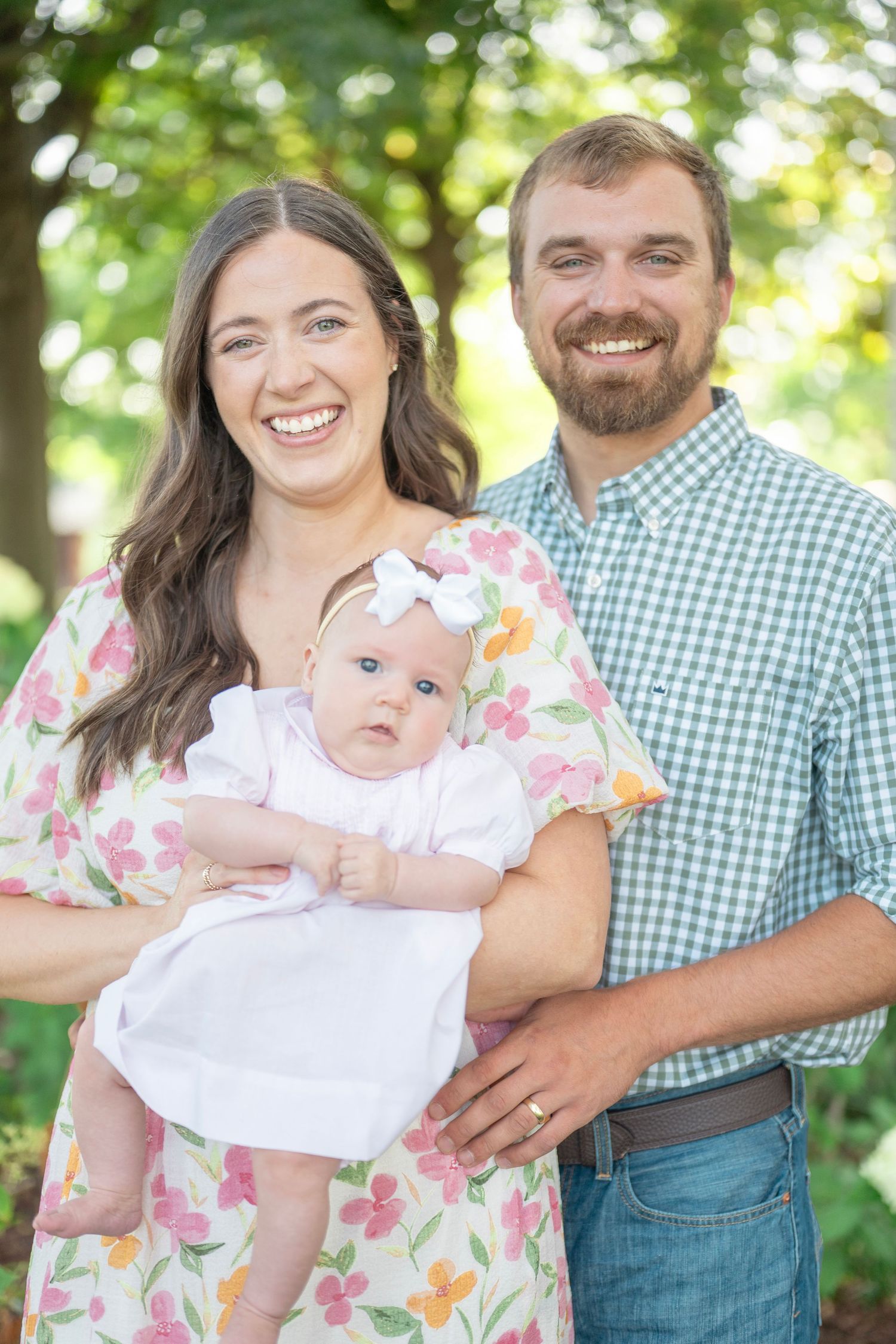Outdoor family portraits in natural setting with floral dress and plaid shirt coordinated outfits.