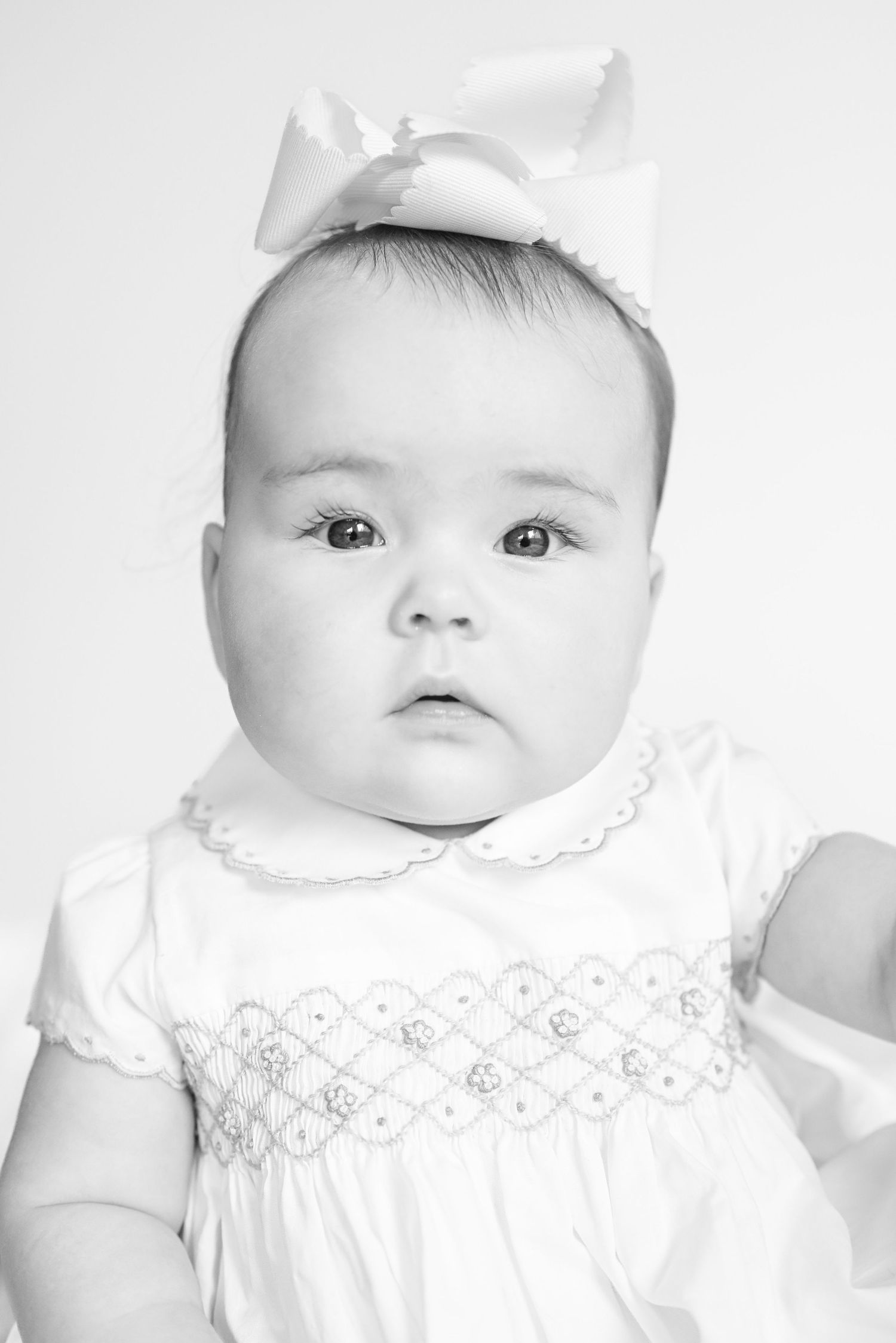 Series of black and white portraits showing baby in delicate white dress with lace details.