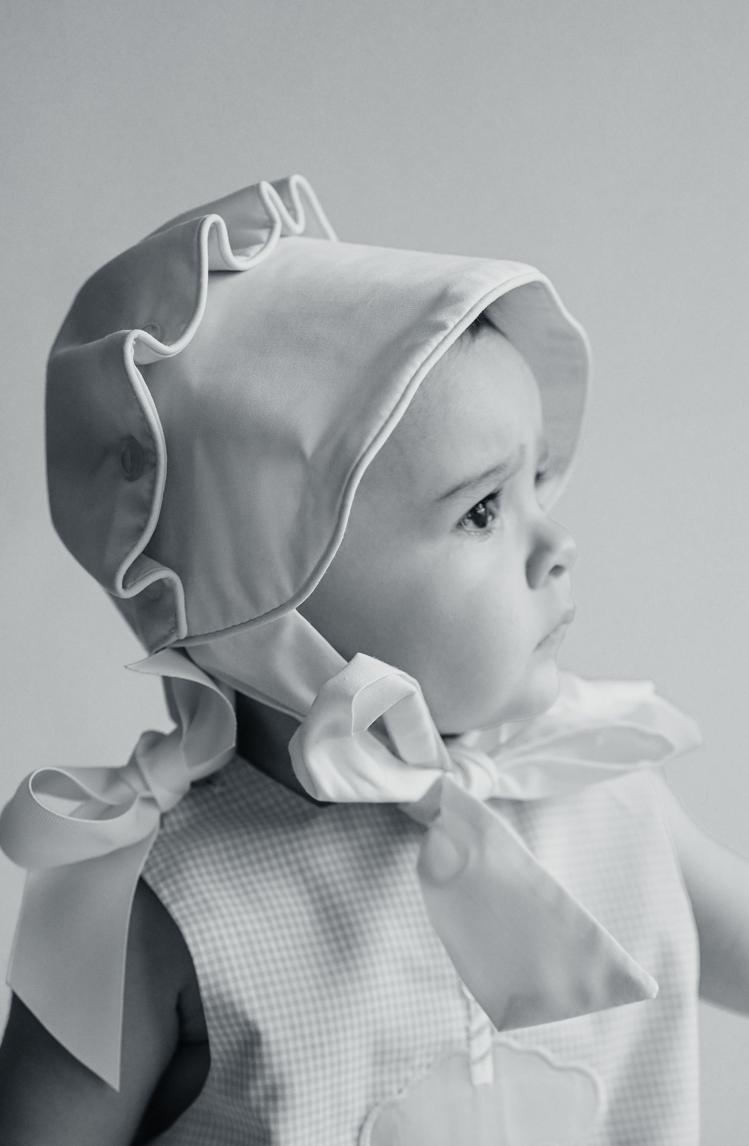 Series of black and white portraits showing baby in ruffled bonnet and classic attire.