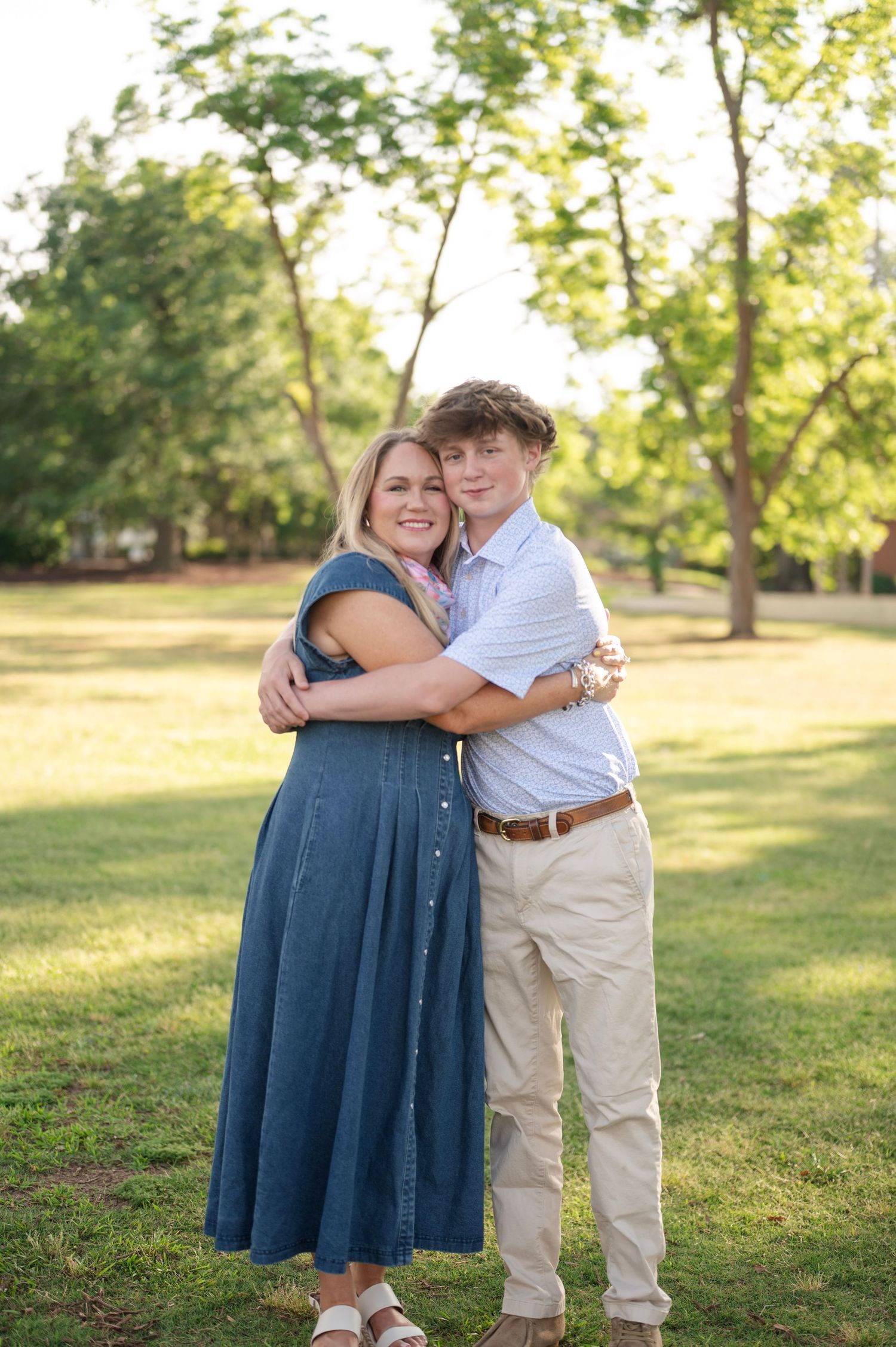 Couple embracing outdoors in a park on sunny day wearing coordinated blue and white outfits.