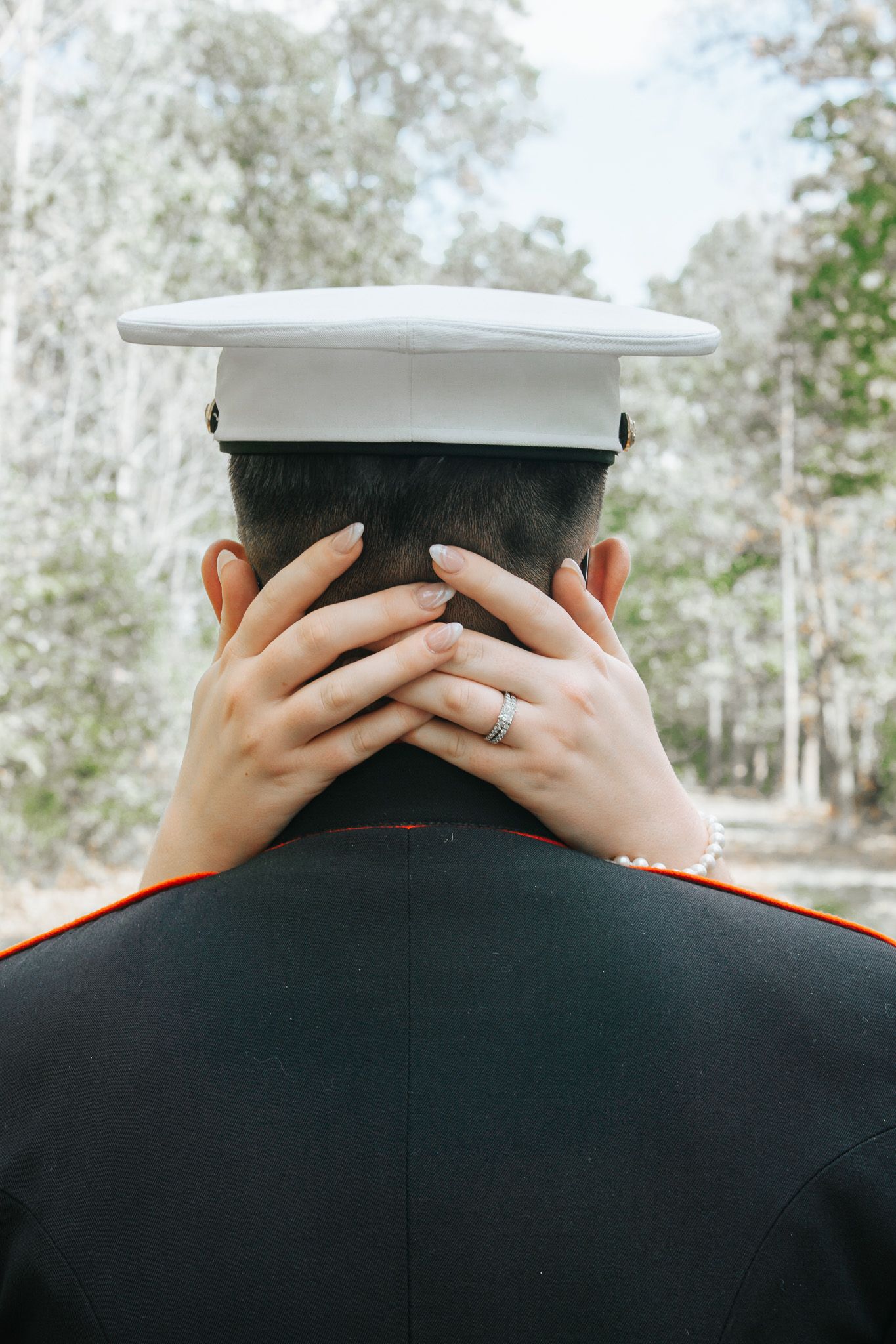 A series of four similar photos showing the back of a military service member wearing a white cap and dark uniform.