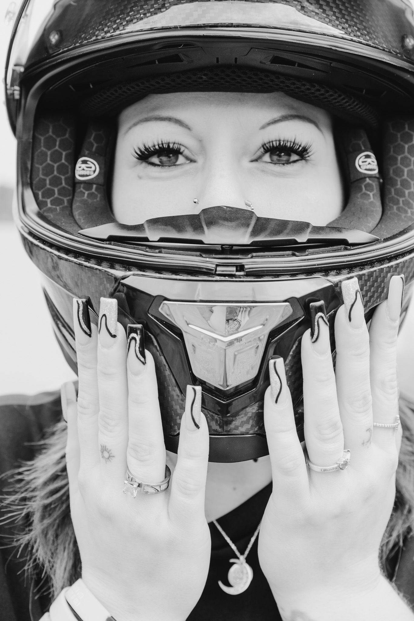 Five sequential shots of a motorcycle rider looking through helmet visor with hands raised in black and white.