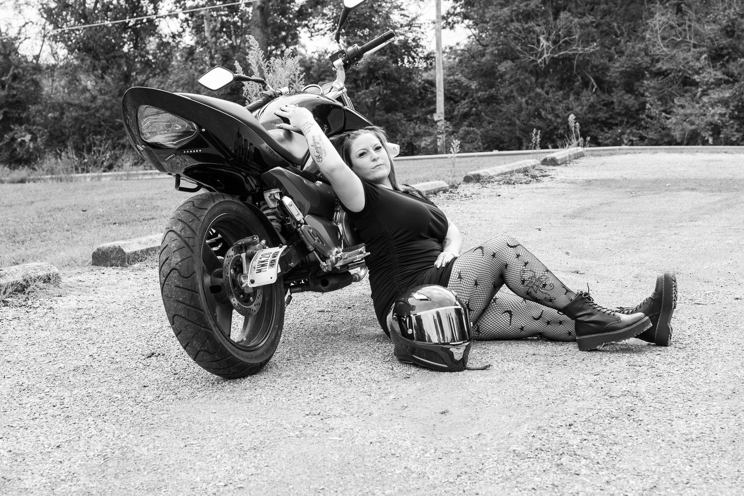 A motorcycle rider lying on asphalt demonstrates maintenance and repair techniques in black and white photos.